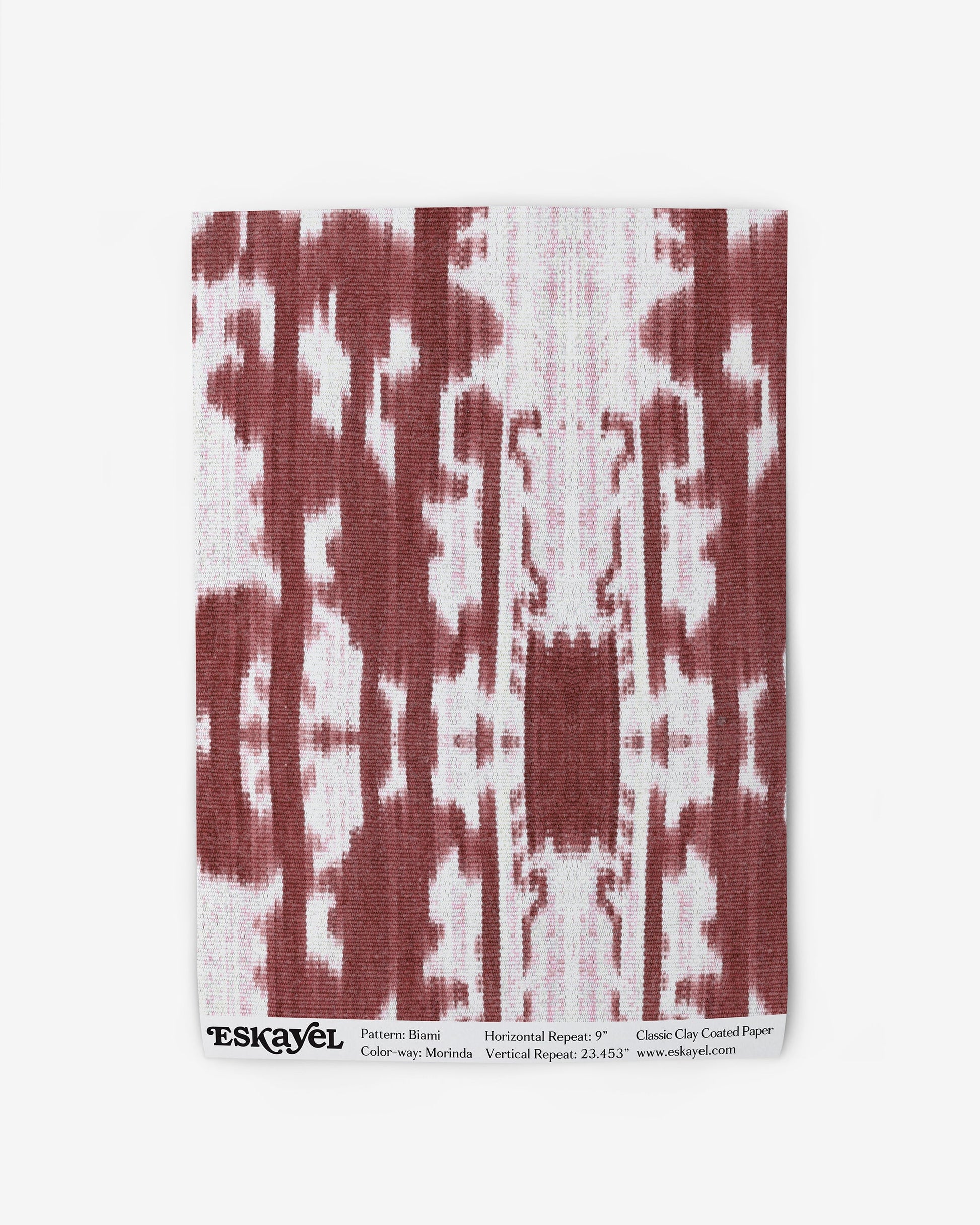 A red and white fabric with a Biami Wallpaper Morinda Ikat pattern on it