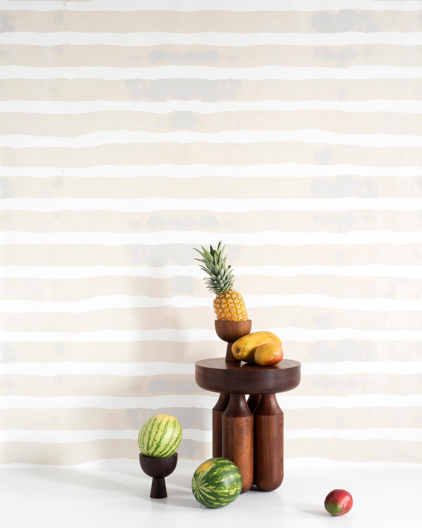 A table with fruit on it from the Bold Stripe Wallpaper Sand Collection by Eskayel