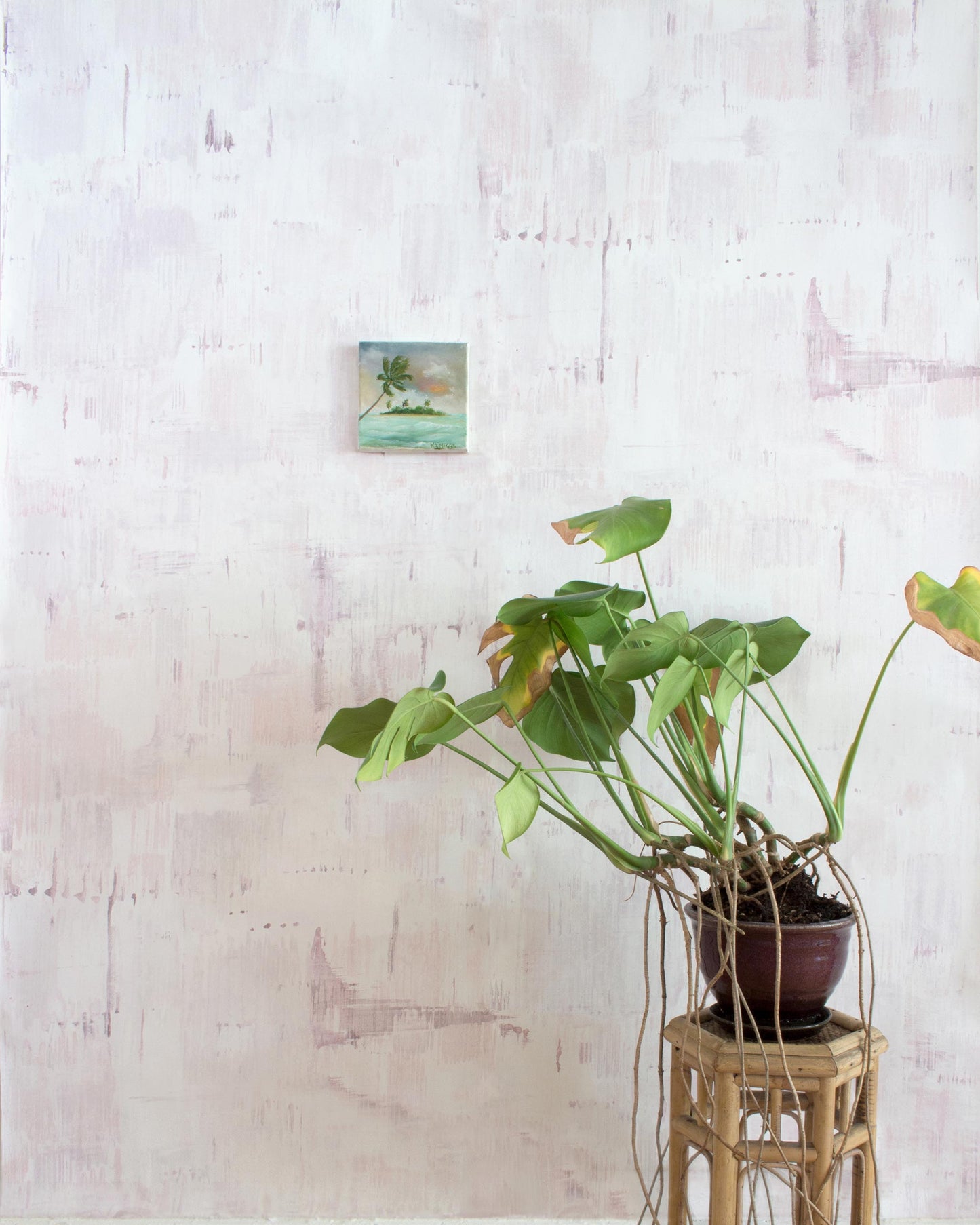 A potted plant sits on a stool in front of a luxury fabric pink wall, adorned with the Cherifia Wallpaper Lumier