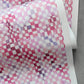 A pink and white checkered Chess Wallpaper Coral fabric on a table