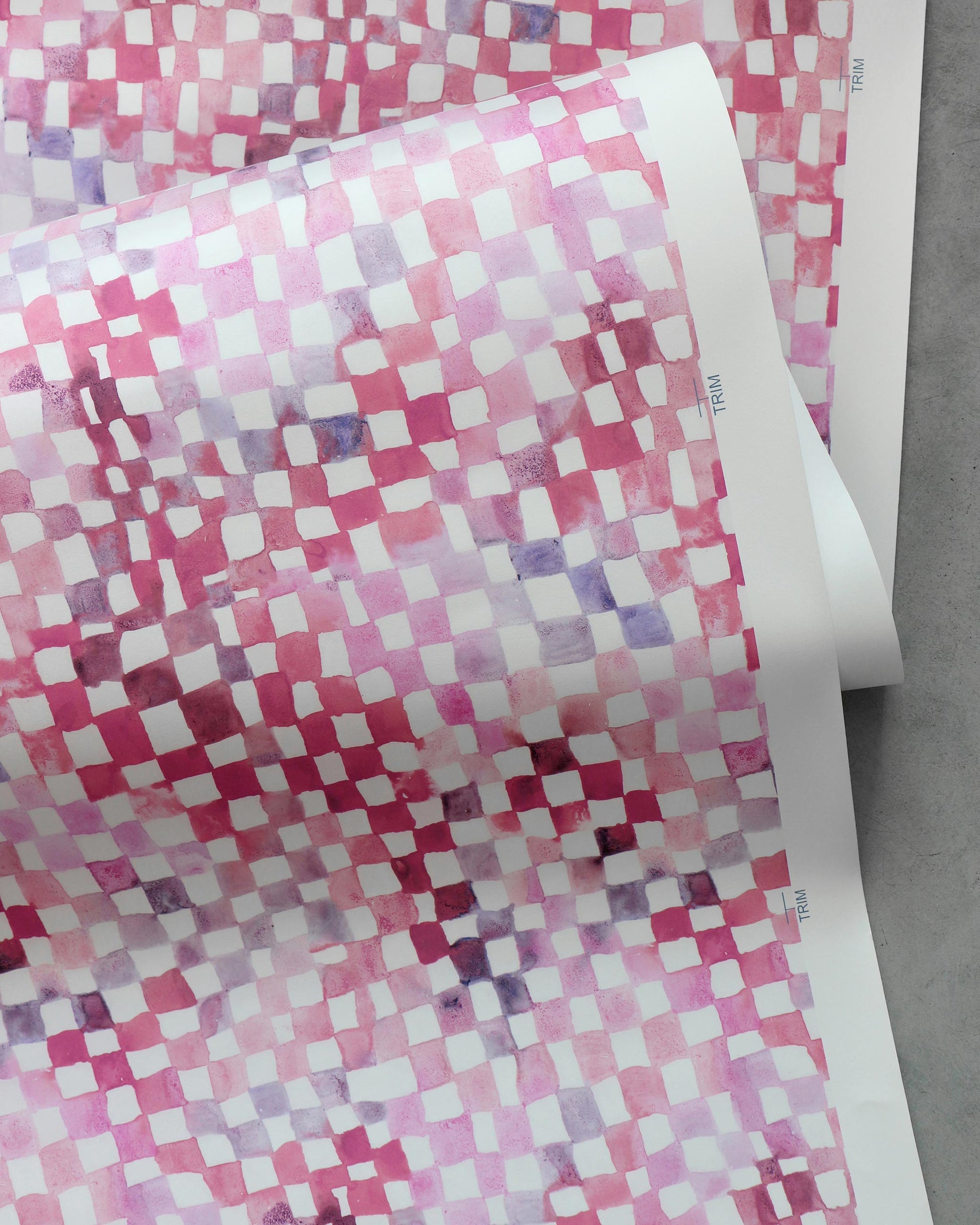 A pink and white checkered Chess Wallpaper Coral fabric on a table