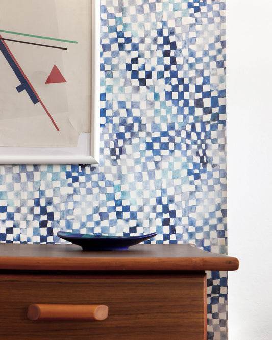 A blue and white Chess Wallpaper Ocean tiled wall behind a dresser