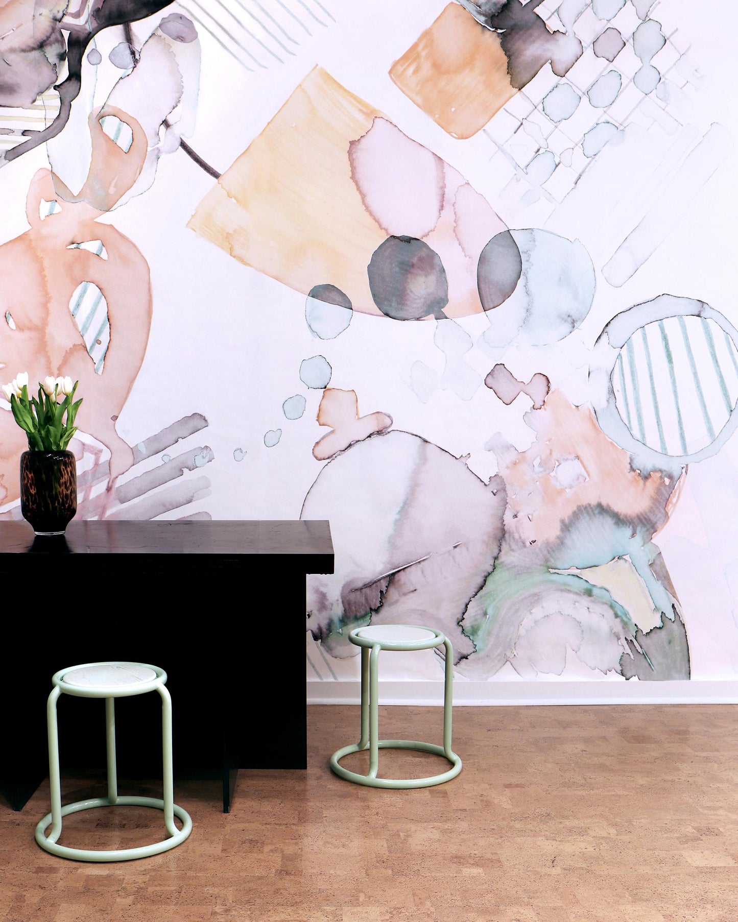 A black table with two stools in front of the Sea Galaxy Wallpaper Reef artwork