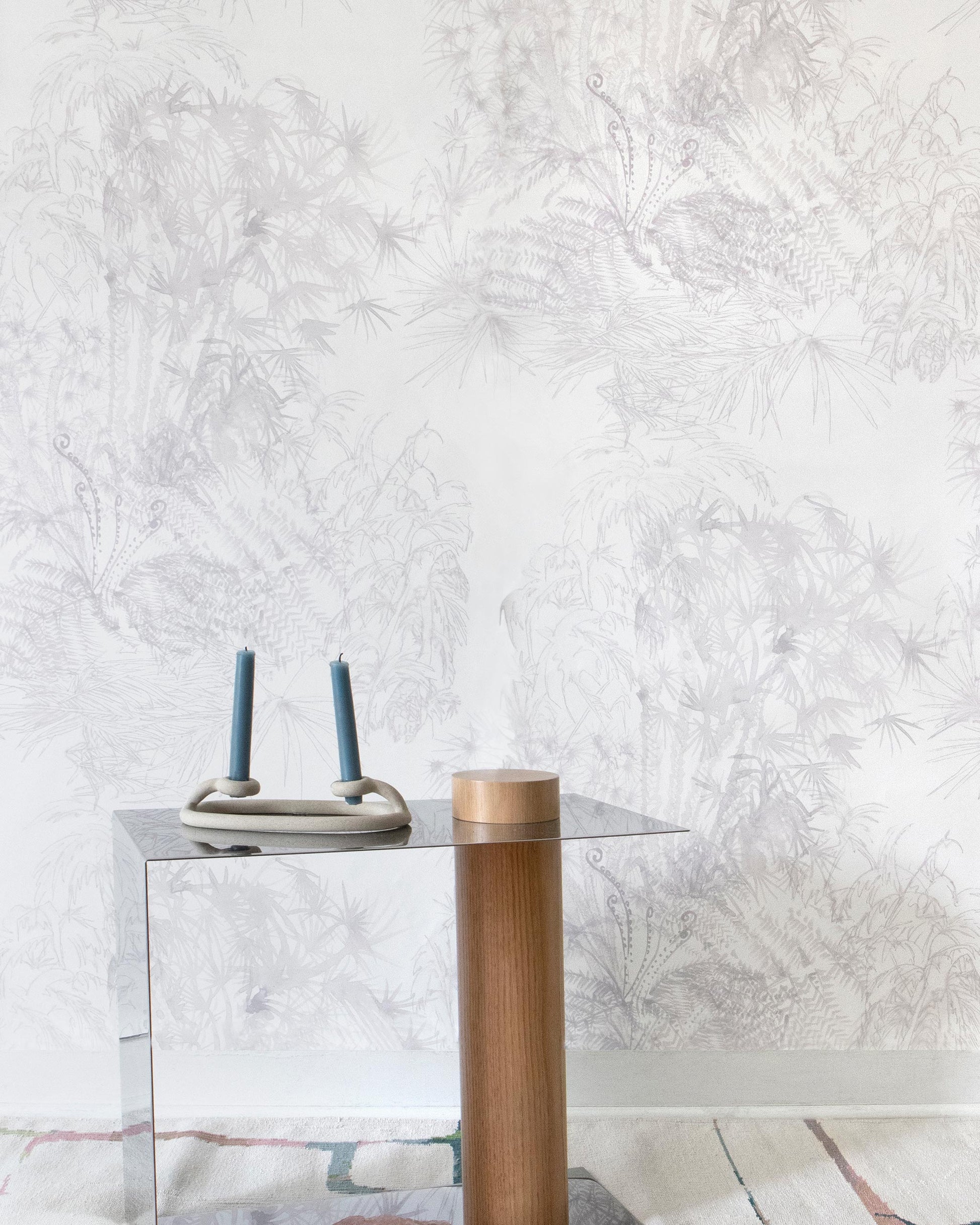 A table with a vase and a lamp in front of a white wall from the Domenica Wallpaper Lumier Collection