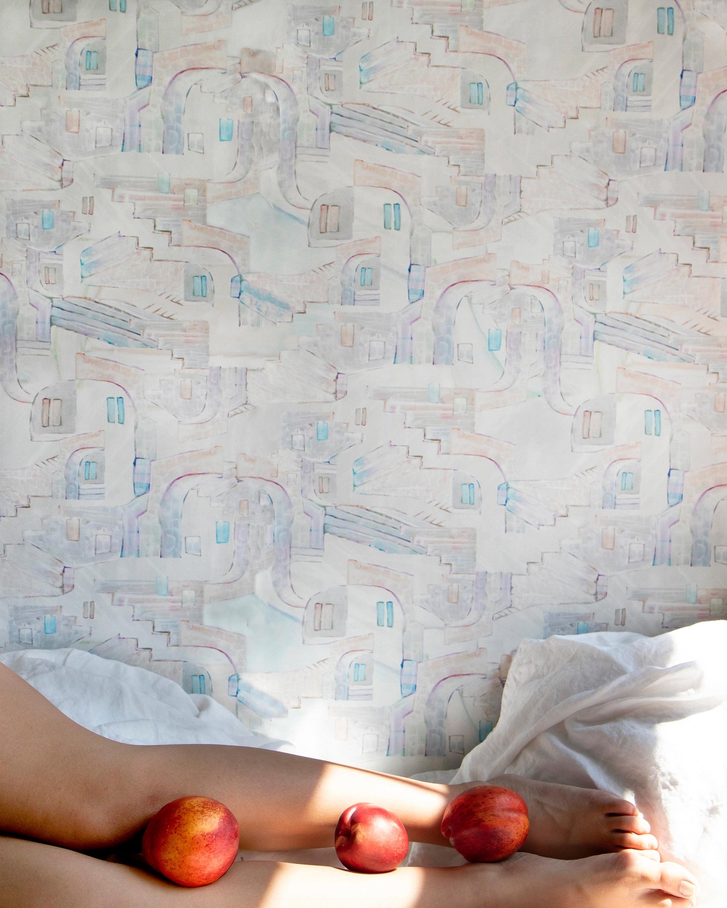 A woman laying on a bed with two apples, surrounded by custom fabric and La Scala Wallpaper Multi luxury