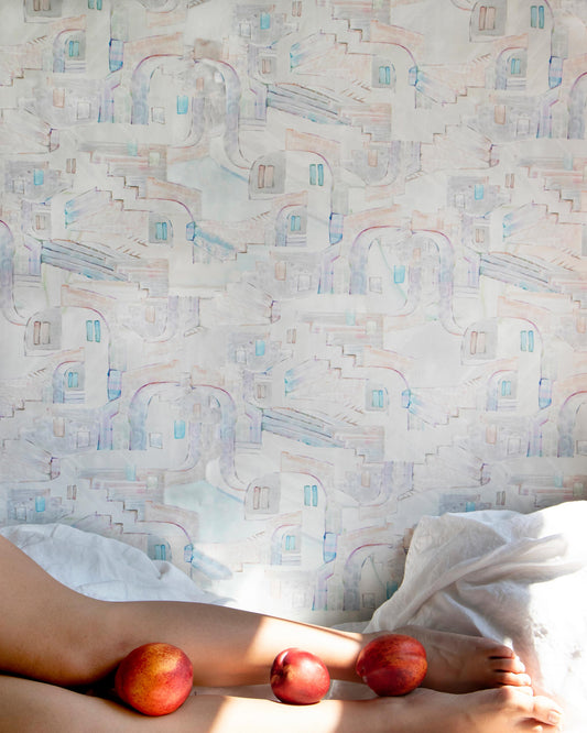 A woman laying on a bed with two apples, surrounded by custom fabric and La Scala Wallpaper Multi luxury