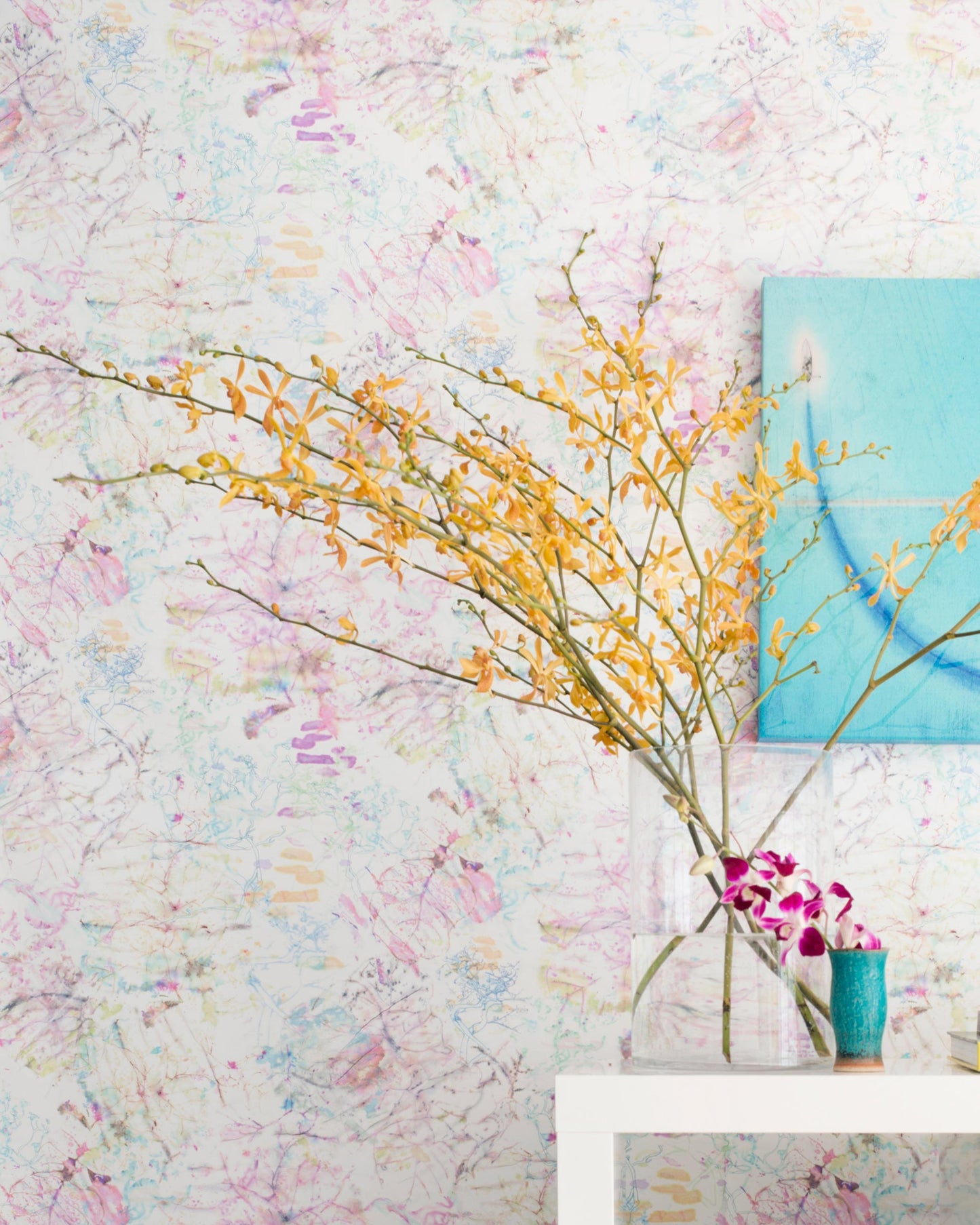 A vase of flowers on a table in front of a colorful Bosky Toile Wallpaper Polychrome