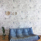 A blue sofa in front of a Cherifia Wallpaper pattern wallpapered wall