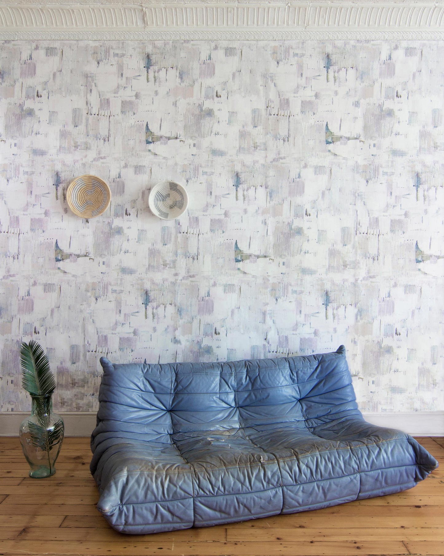 A blue sofa in front of a Cherifia Wallpaper pattern wallpapered wall