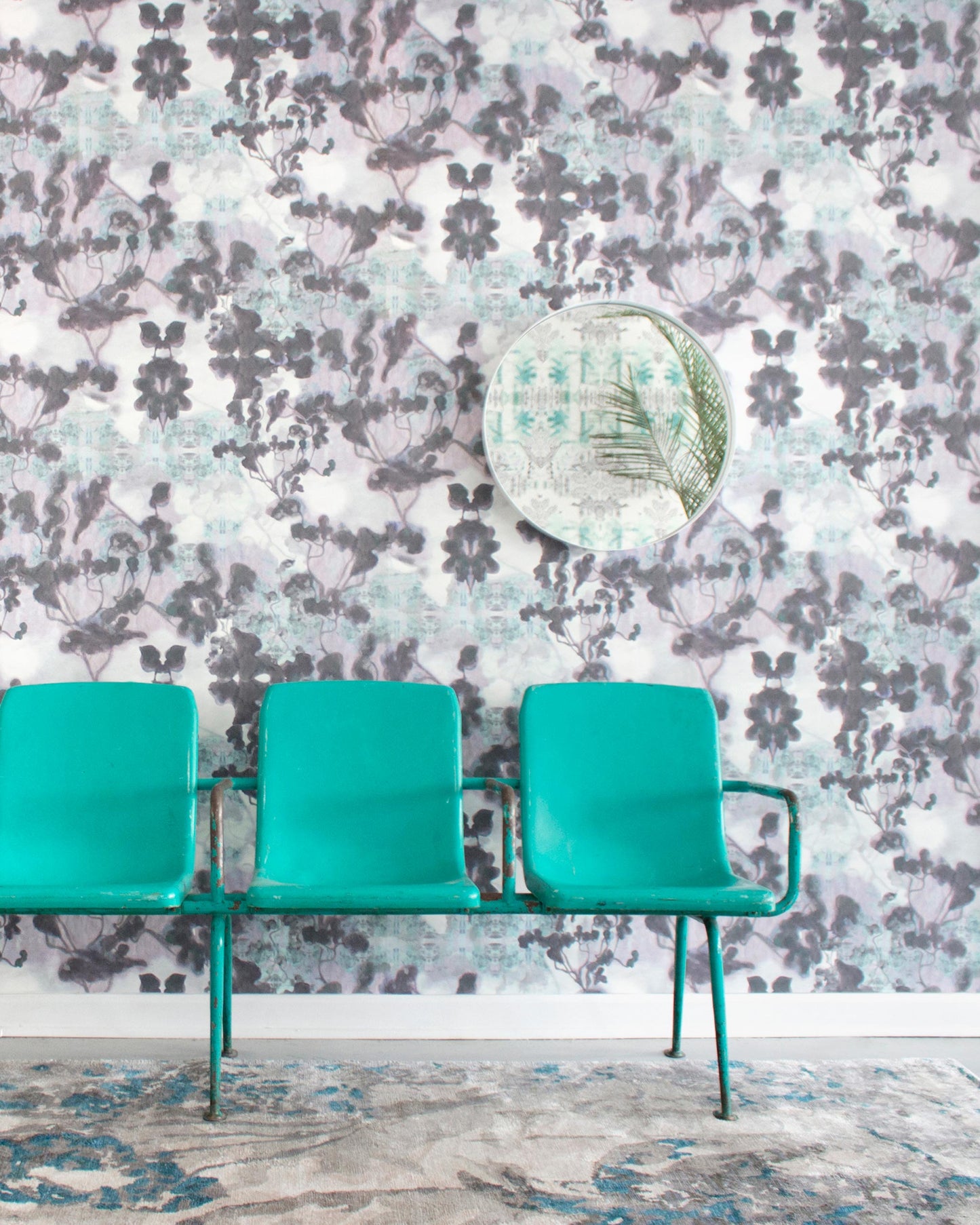 Two teal chairs in front of a wall with a floral pattern adorned with custom wallpaper from the Clemente Wallpaper Canyon