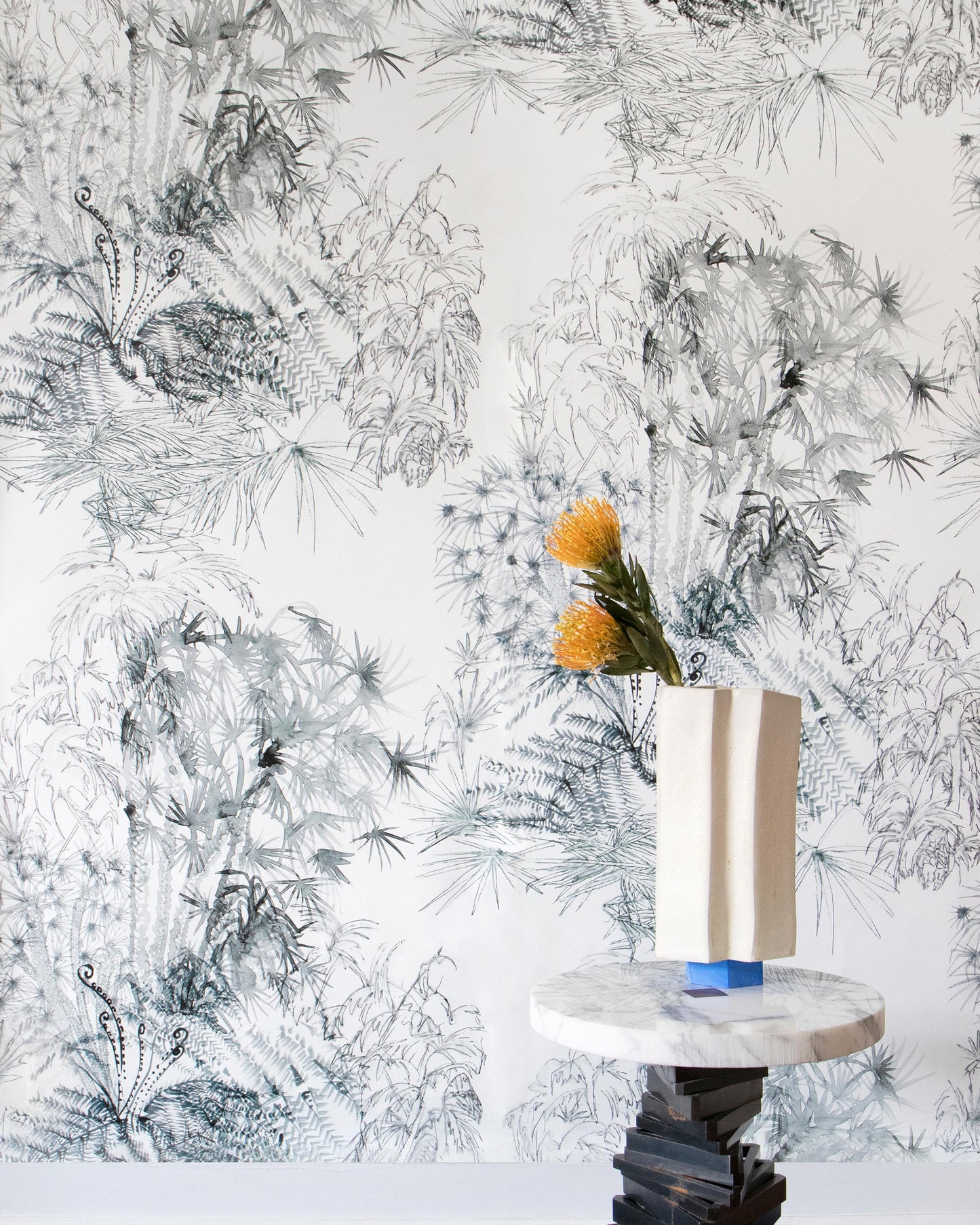 A vase on a table showcasing the Domenica Wallpaper Notte pattern from the Salentu Collection in front of a luxurious fabric