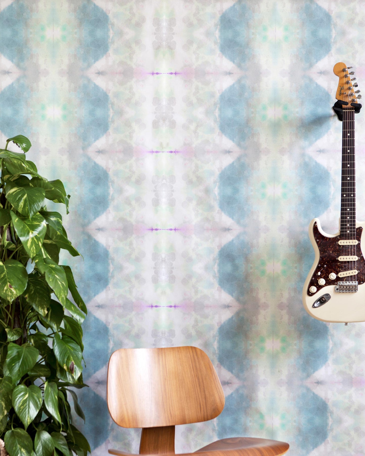 Jangala Wallpaper is sitting on a chair in front of a colorful fabric