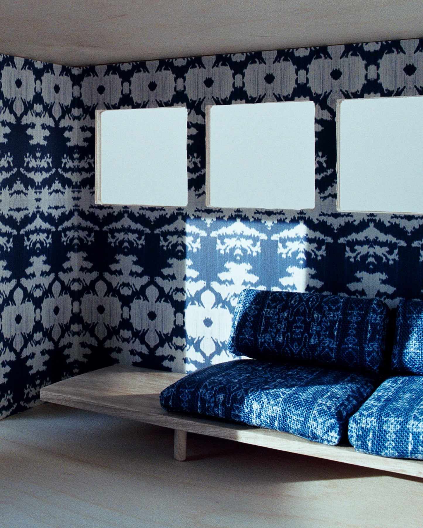 A room with a couch and two windows, featuring The Dance Wallpaper Indigo Ikat