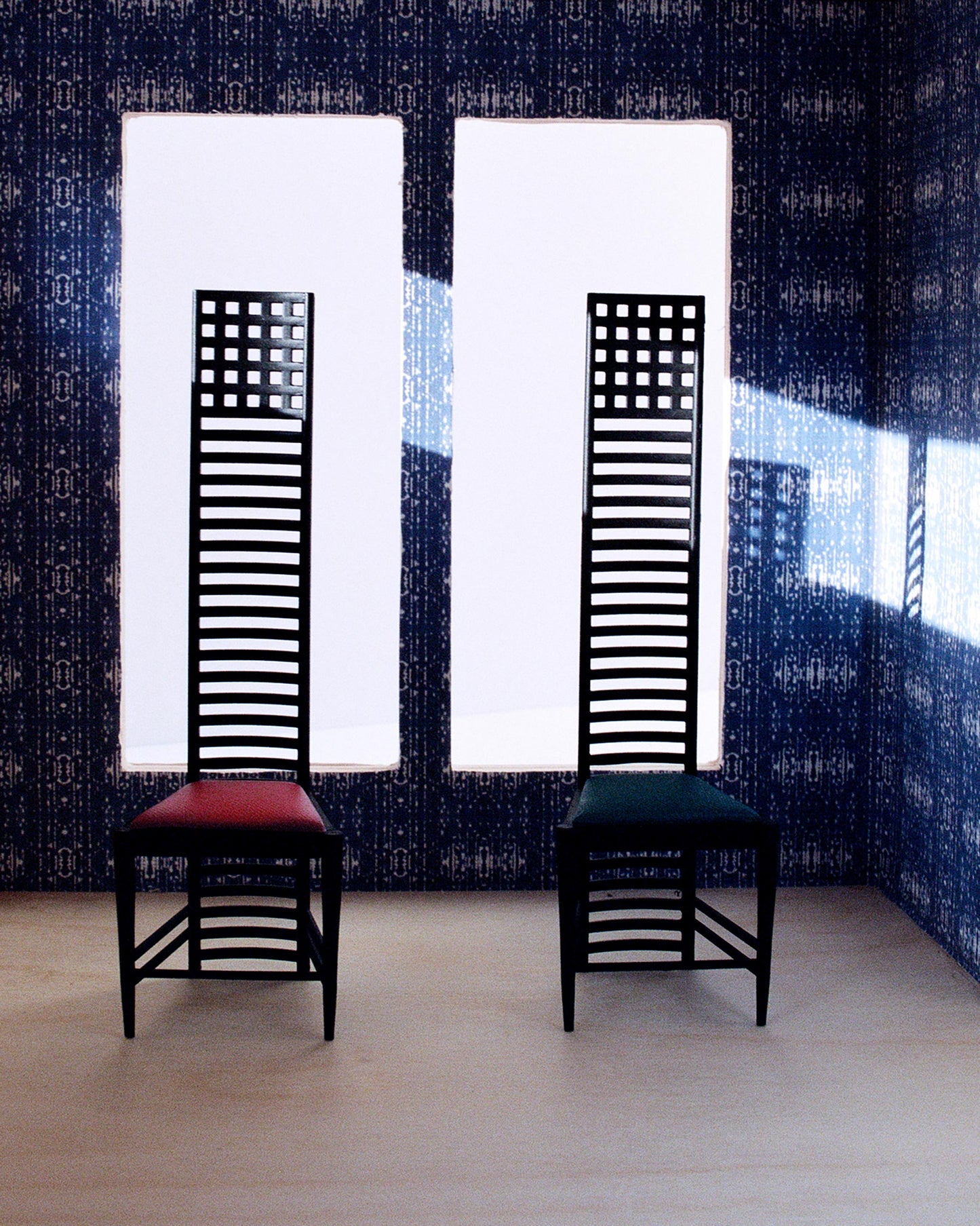 Two chairs in a room with a blue wall, adorned with Omaha Kinship Wallpaper Indigo Ikat's high-end fabrics
