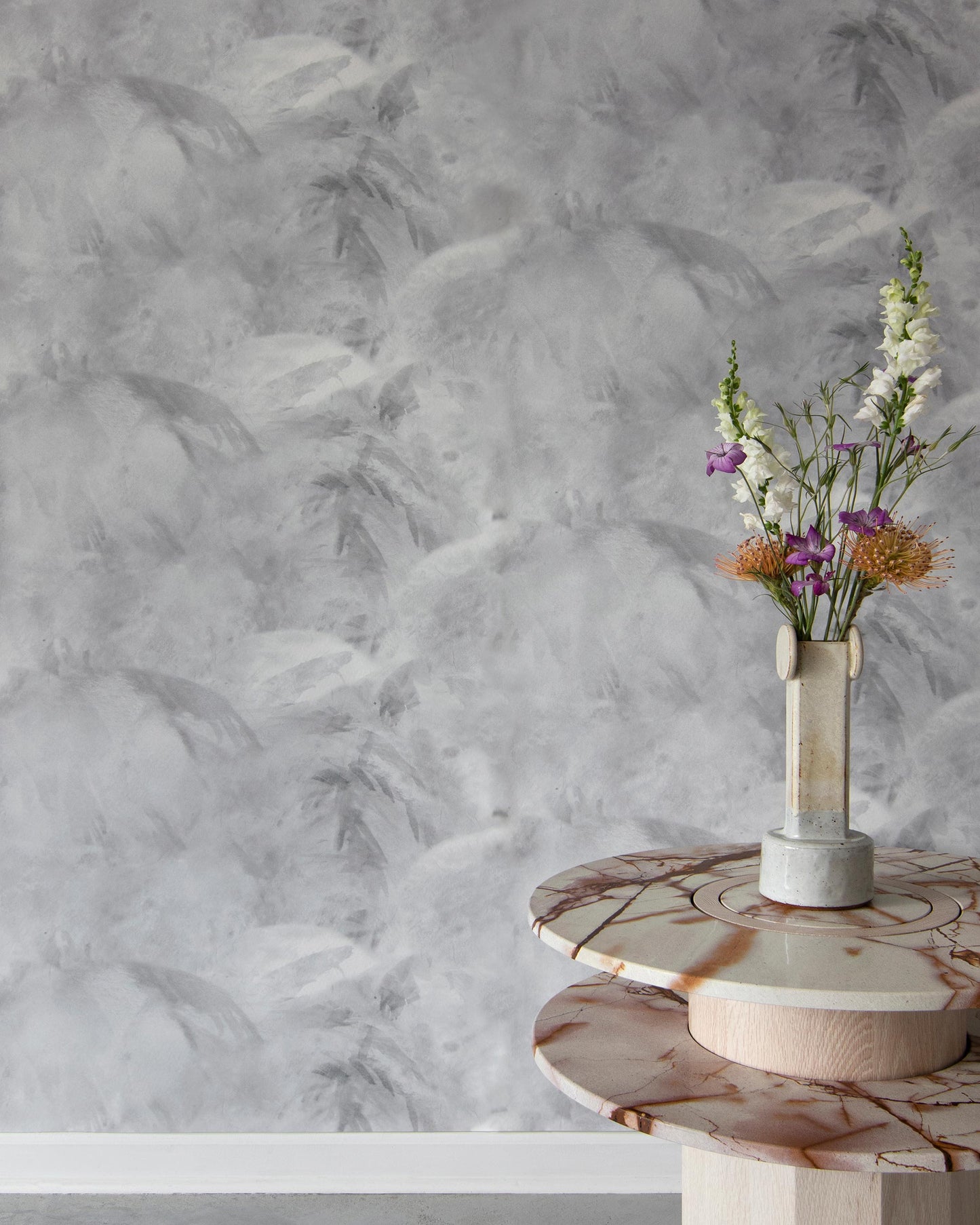 A marble table with a vase in front of it, showcasing a Palmeti Wallpaper Alba fabric pattern