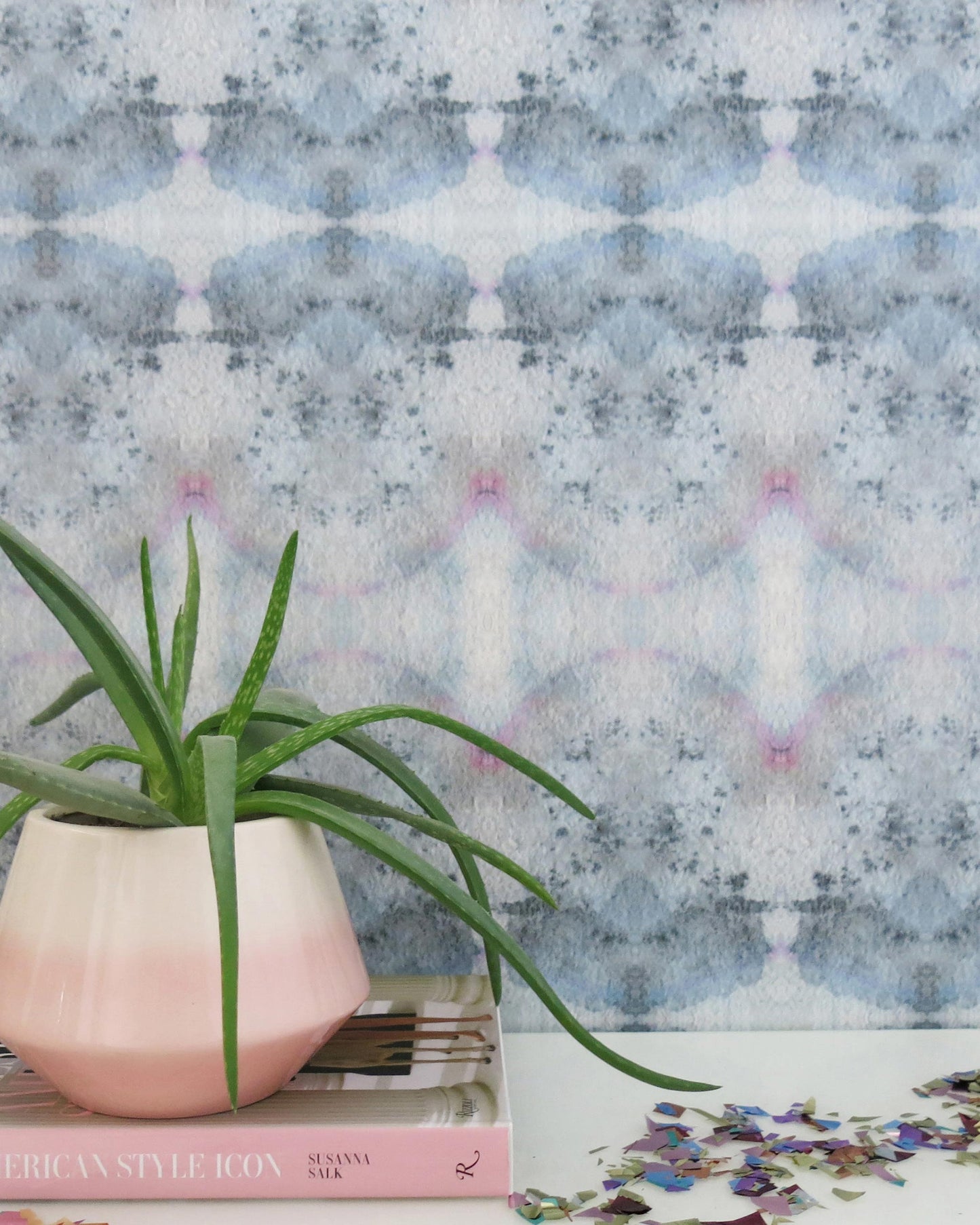 A pink potted Parvati Wallpaper on a table next to a blue