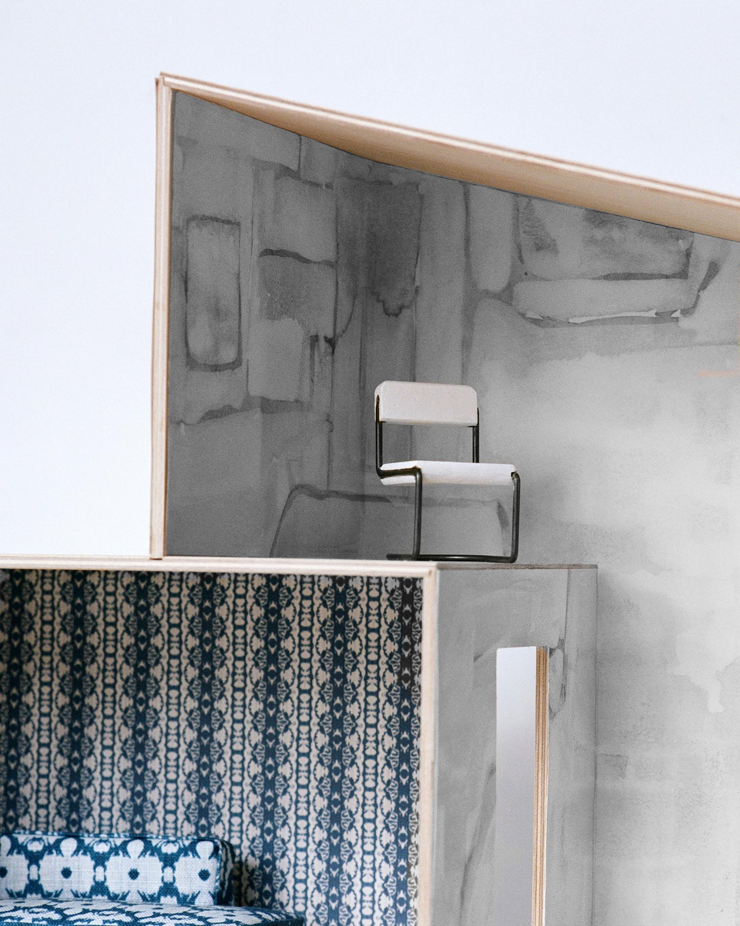 A model of a house with a bed and a chair in Portico Wallpaper Mural Greyscale colorway