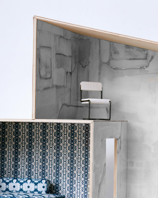 A model of a house with a bed and a chair in Portico Wallpaper Mural Greyscale colorway