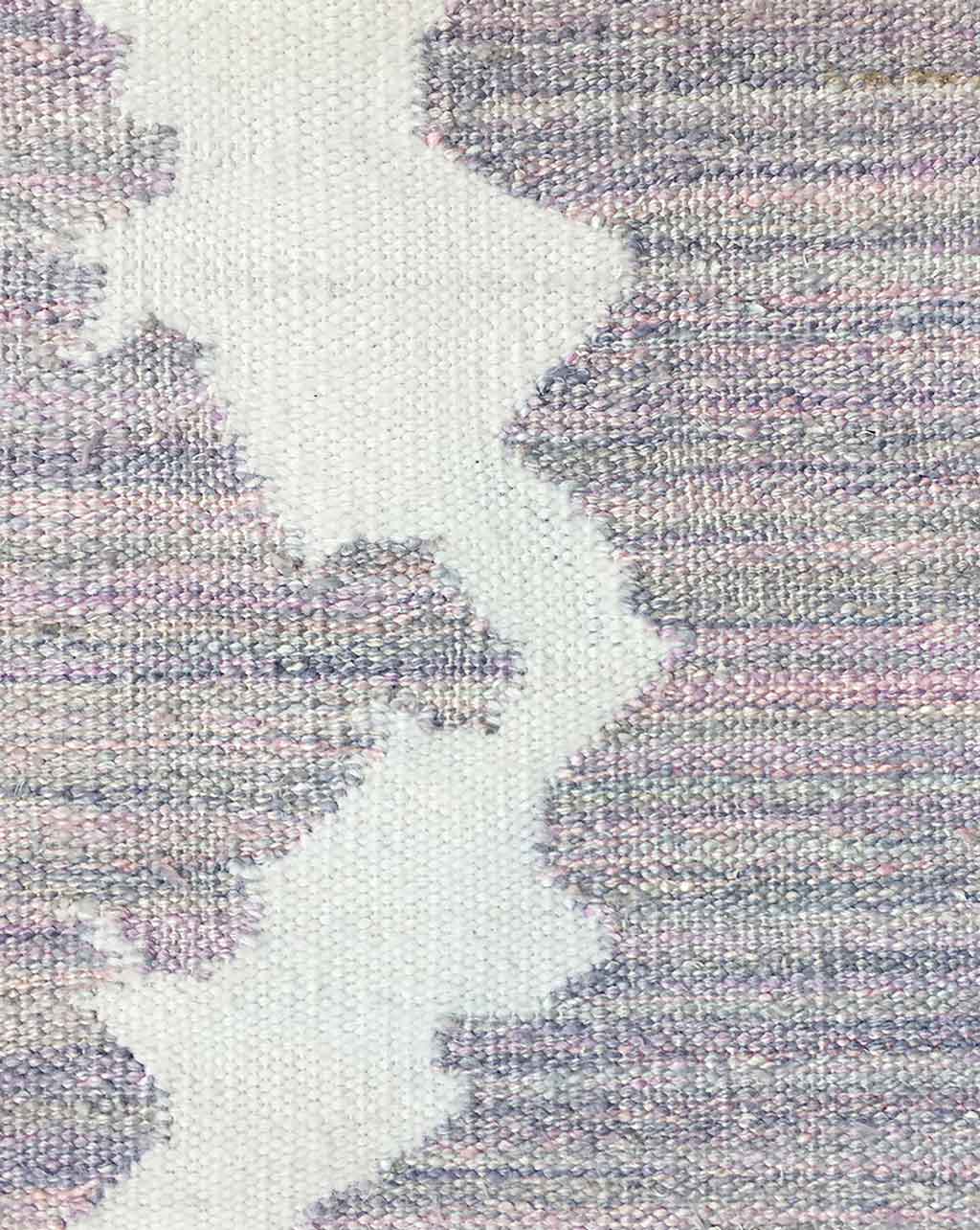 A close up of The Dance Flatweave Rug with a pink and white design