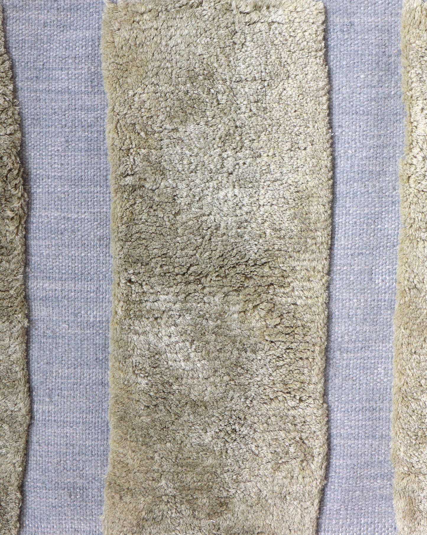 Four strips of beige wool in a bold stripe on a blue background