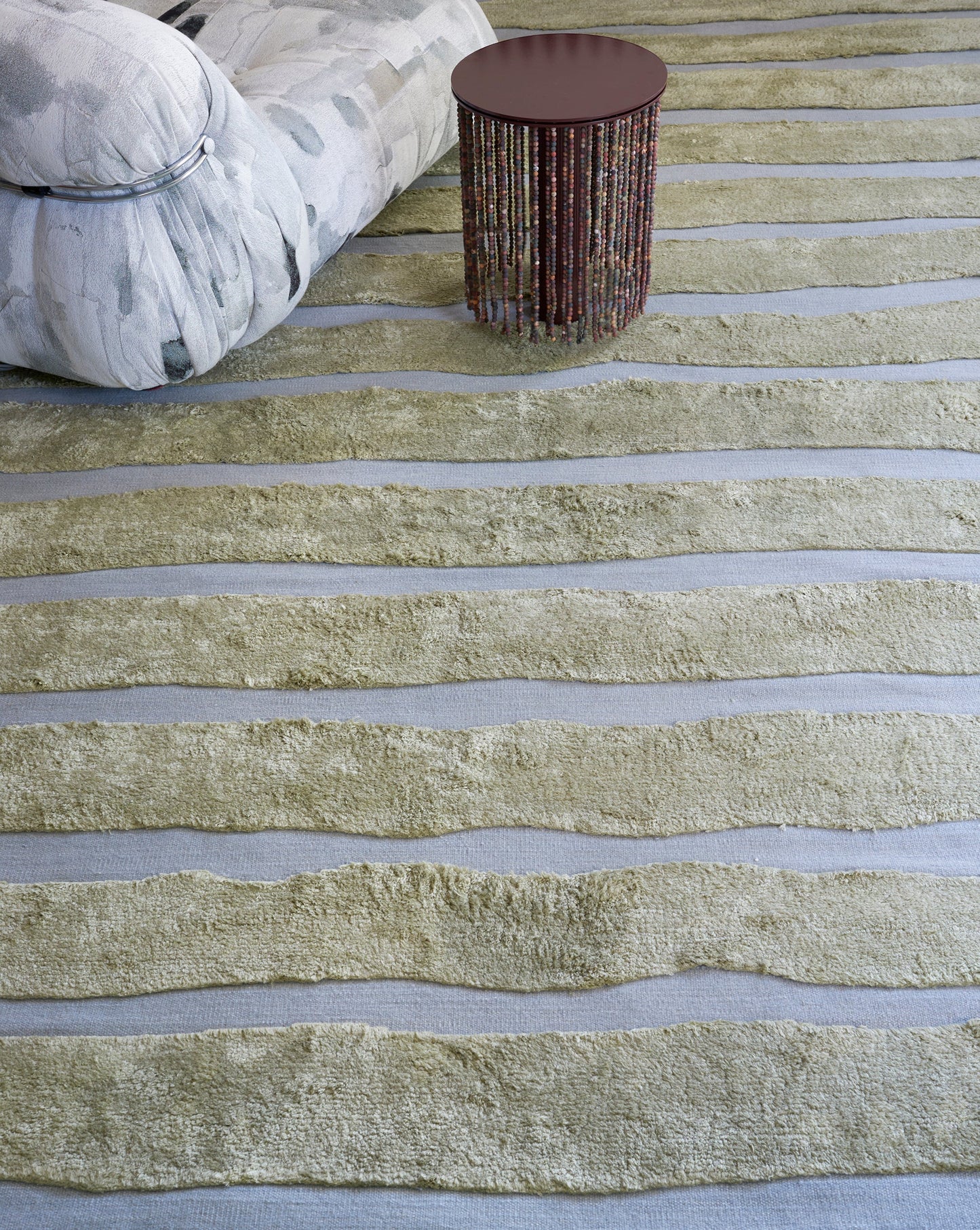 A living room with a Bold Stripe Hand Knotted Rug in Gulf on the floor