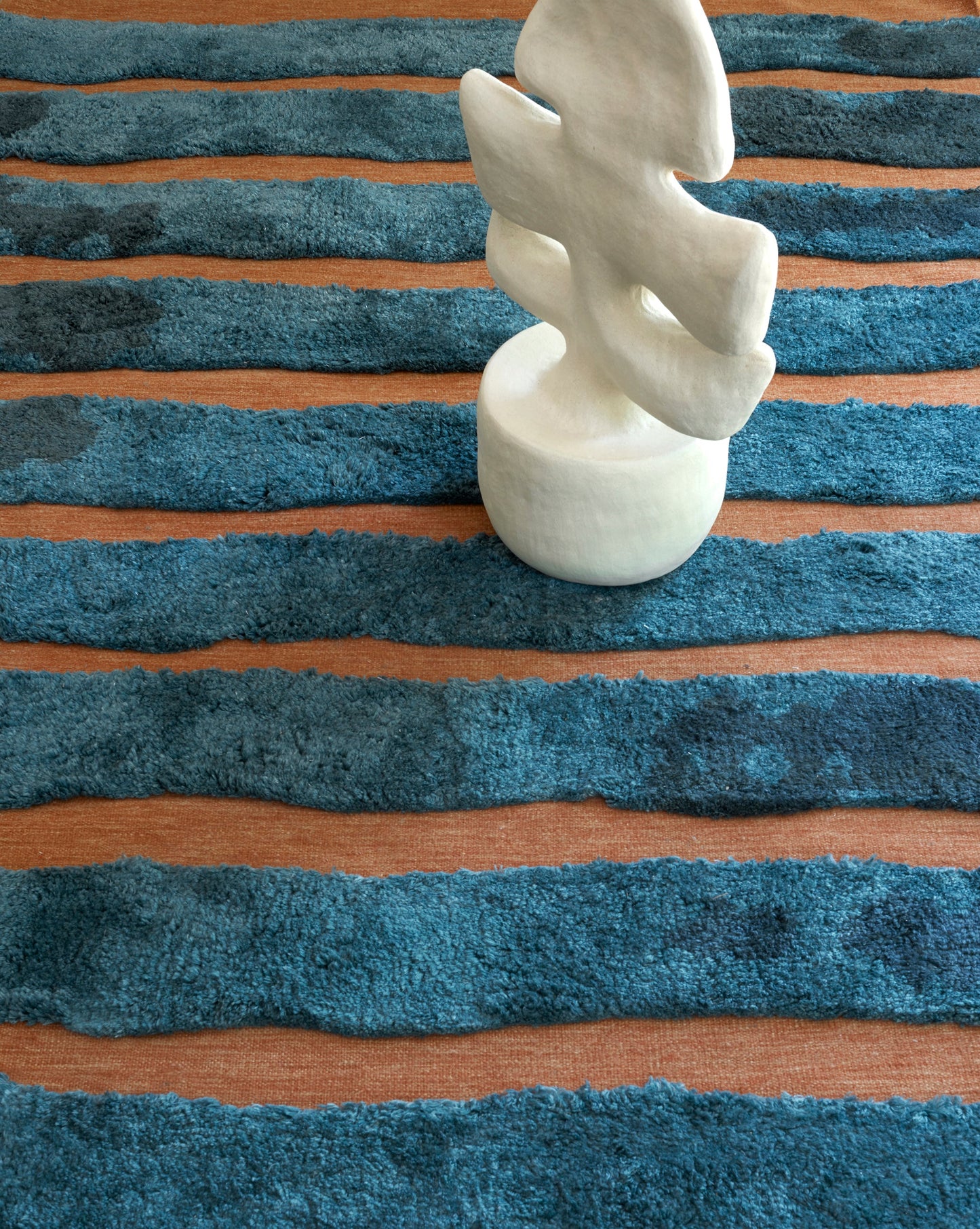 A Bold Stripe Hand Knotted Rug with high-pile blue stripes on a wooden floor