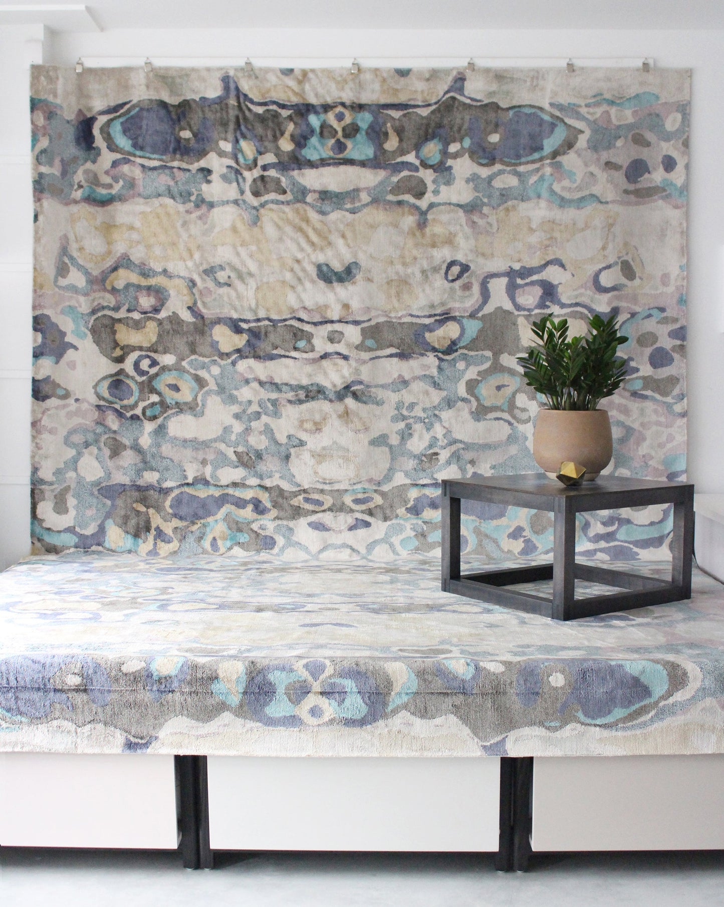 A bed in a room with an Expo Hand Knotted Rug Multi on top of it