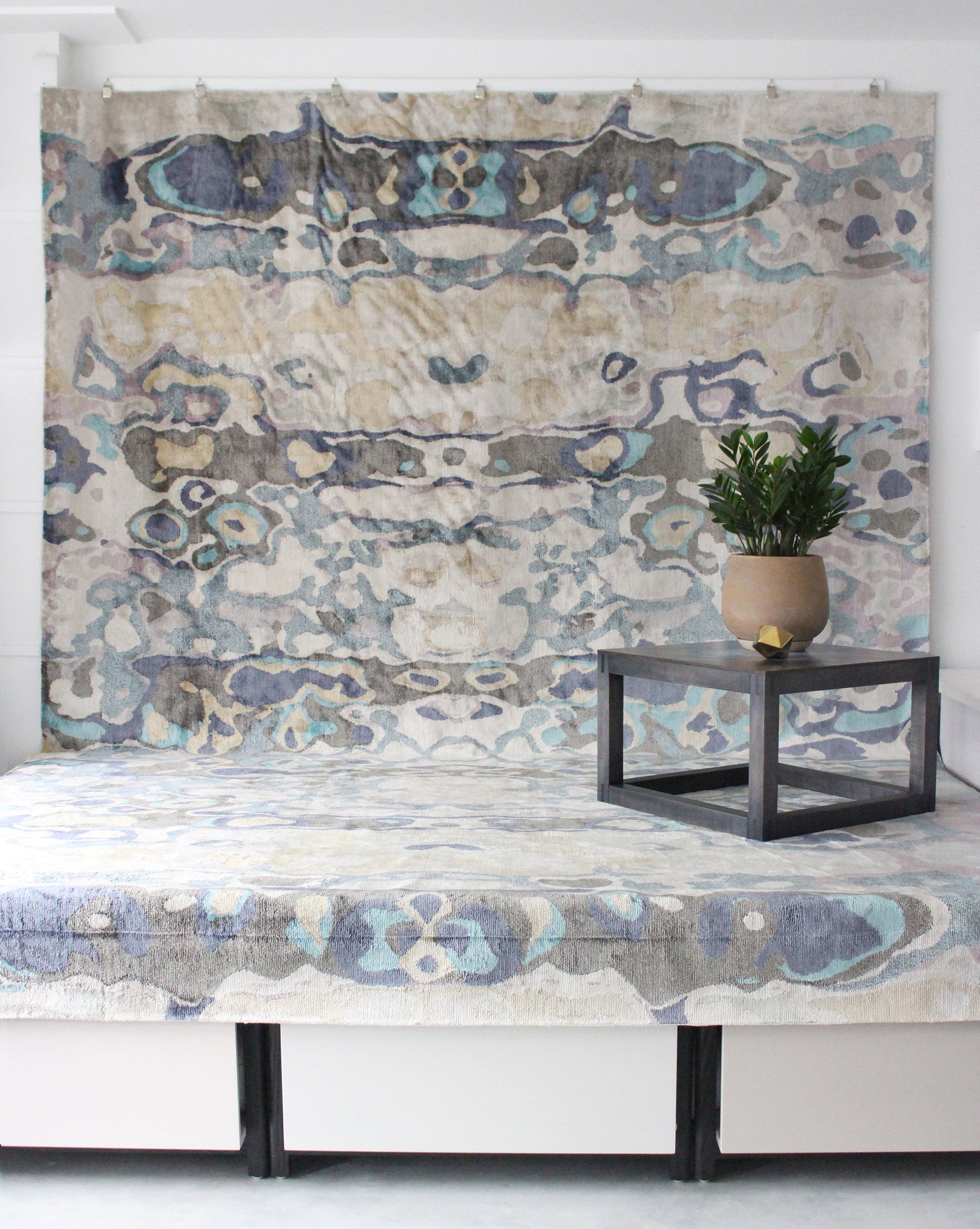 A bed in a room with an Expo Hand Knotted Rug Multi on top of it