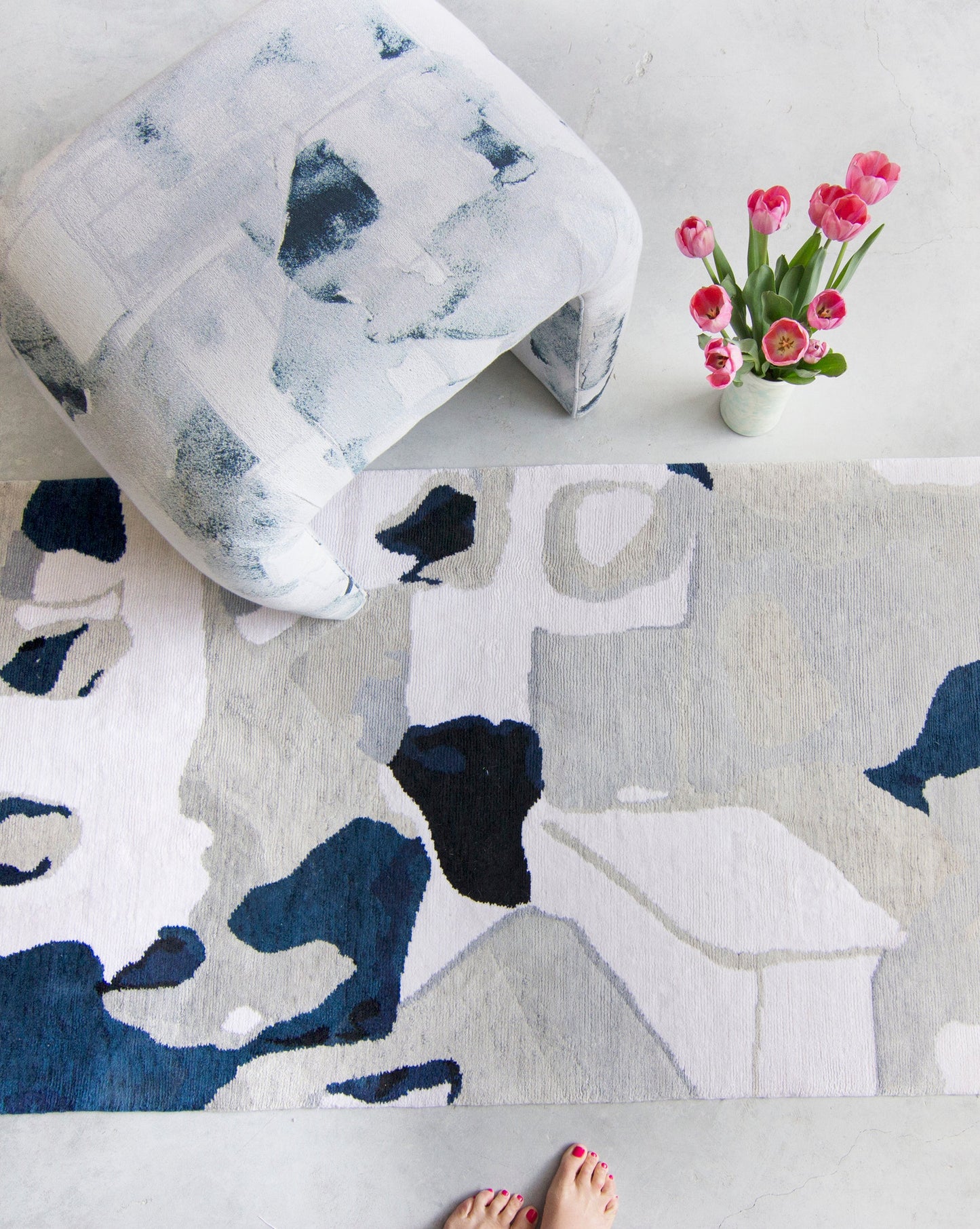 A woman's feet on a Medina Hand Knotted Rug next to a flower