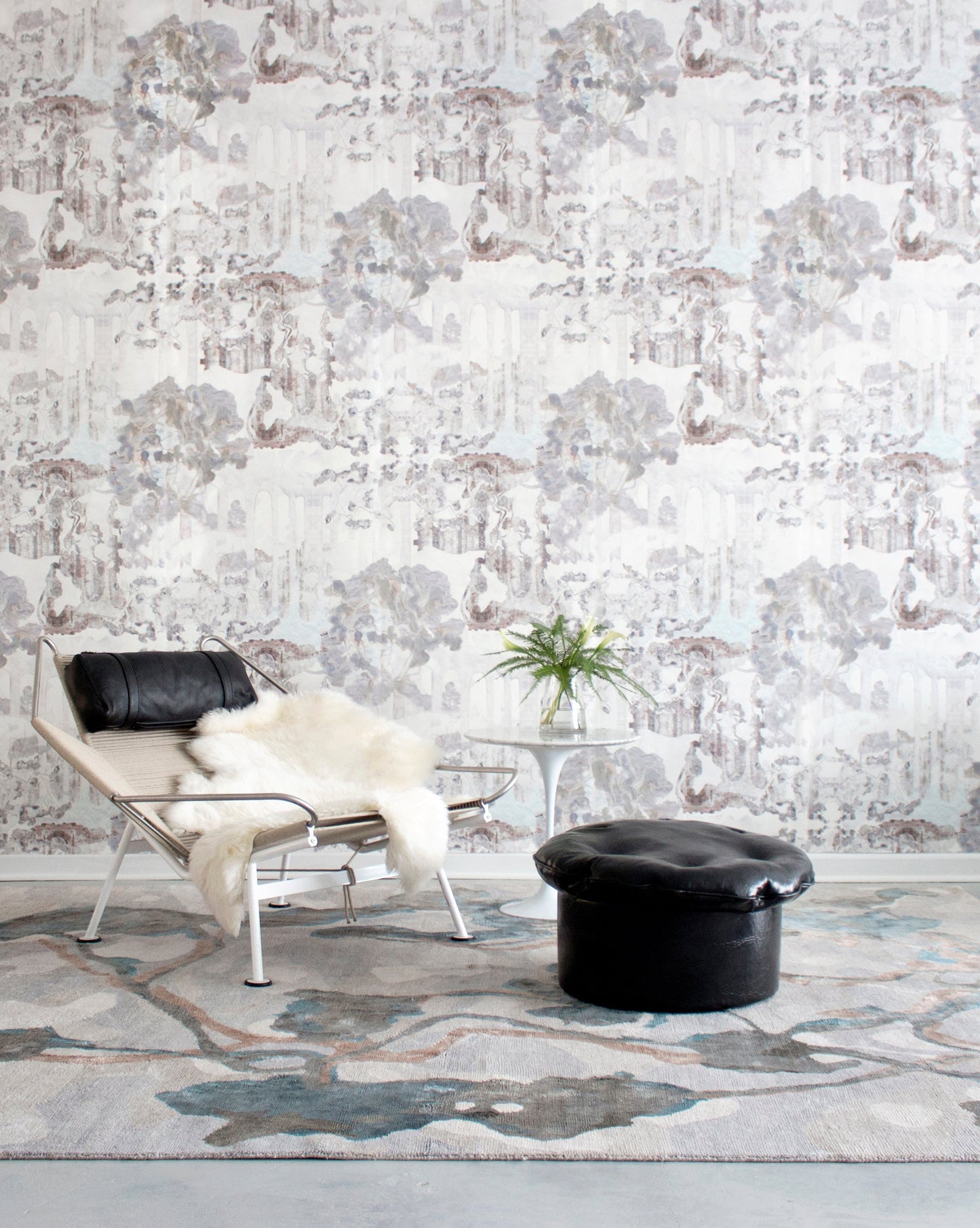 A room with a chair and a Kalypto Hand Knotted Rug Umber pattern on the wall
