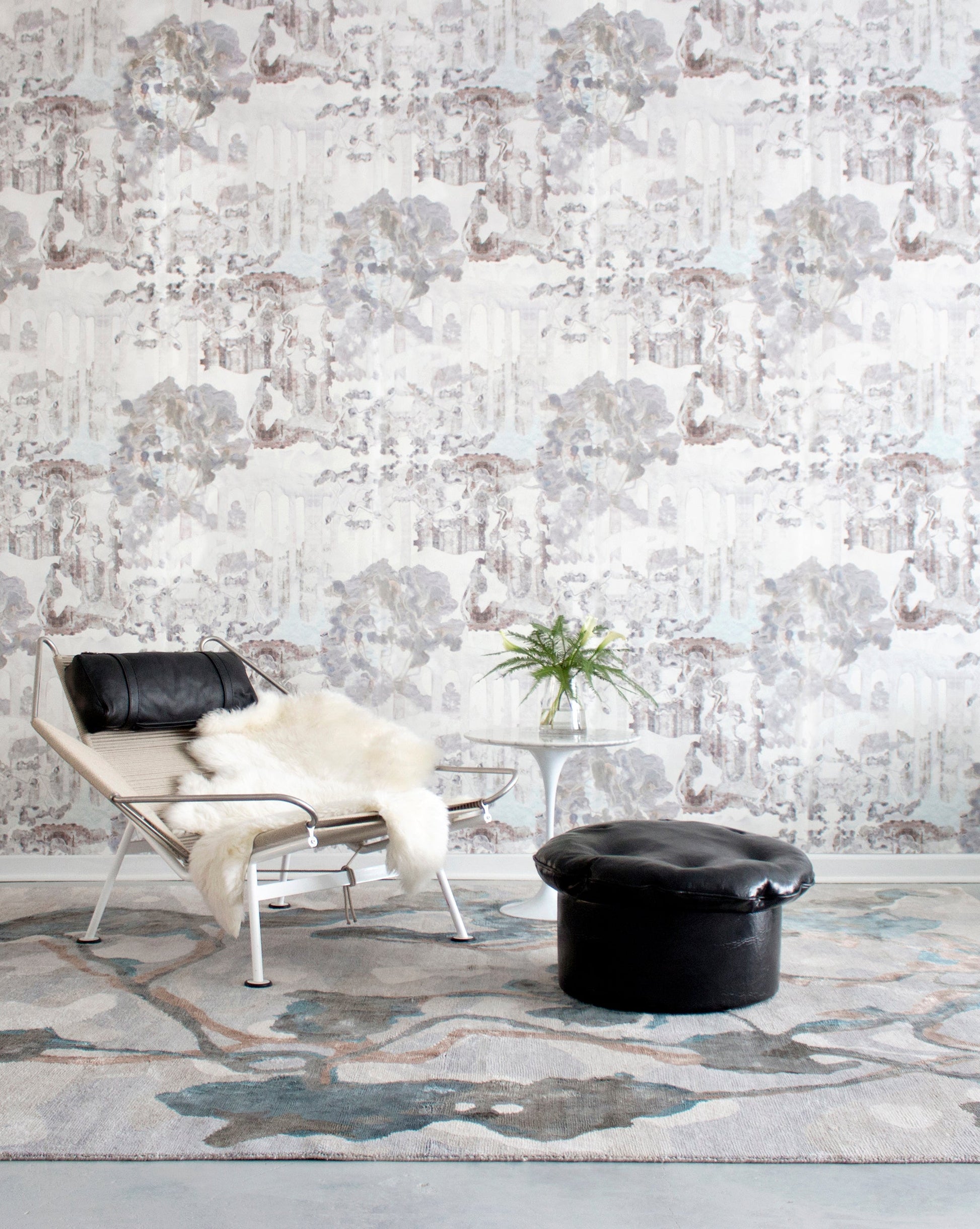 A room with a chair and a Kalypto Hand Knotted Rug Umber pattern on the wall