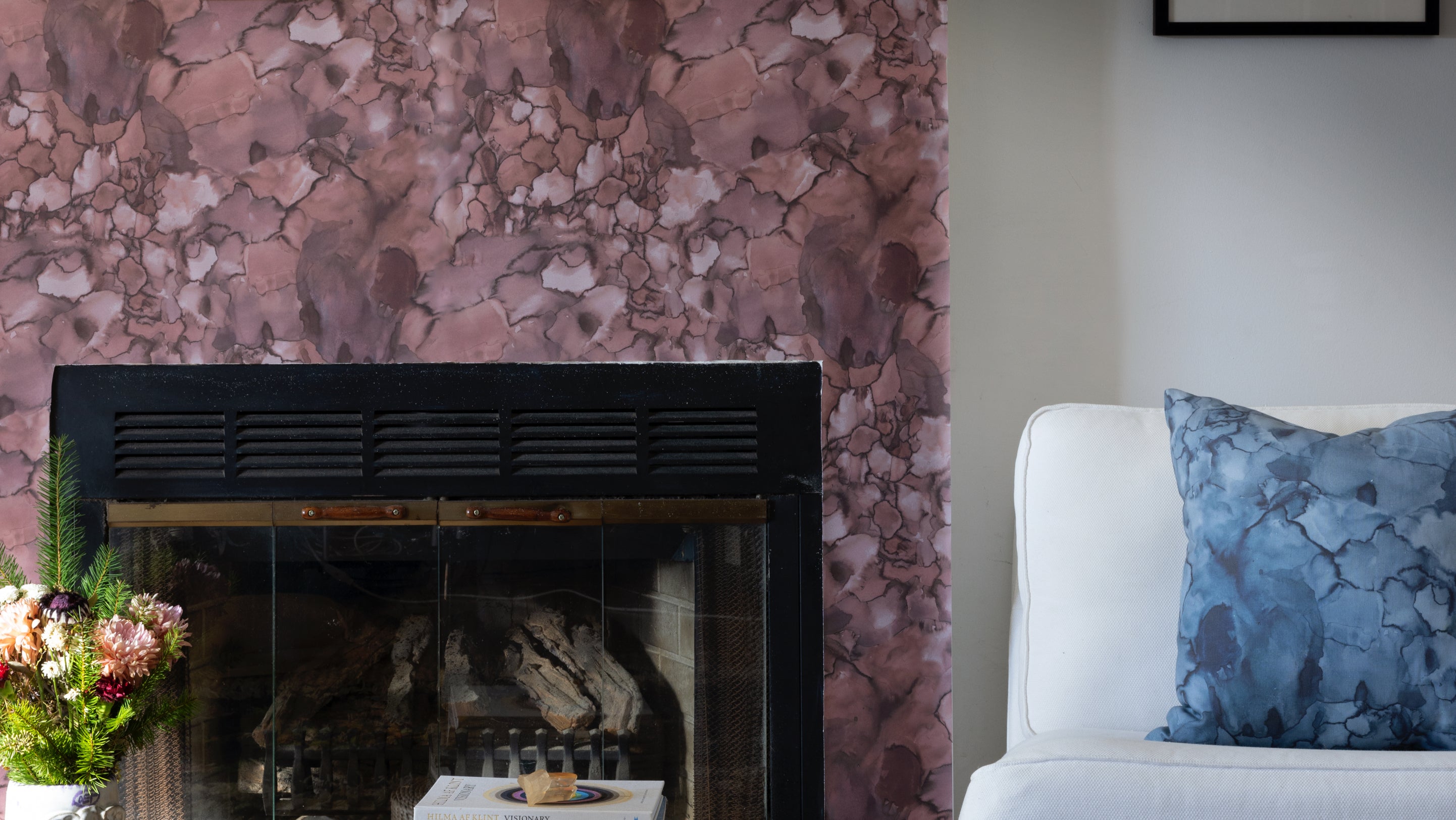 A living room with a fireplace and pink wallpaper
