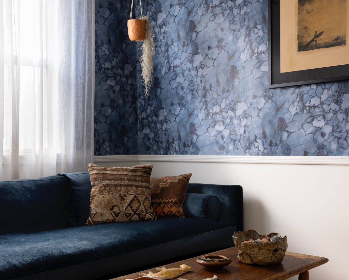 A living room with a blue couch and floral wallpaper