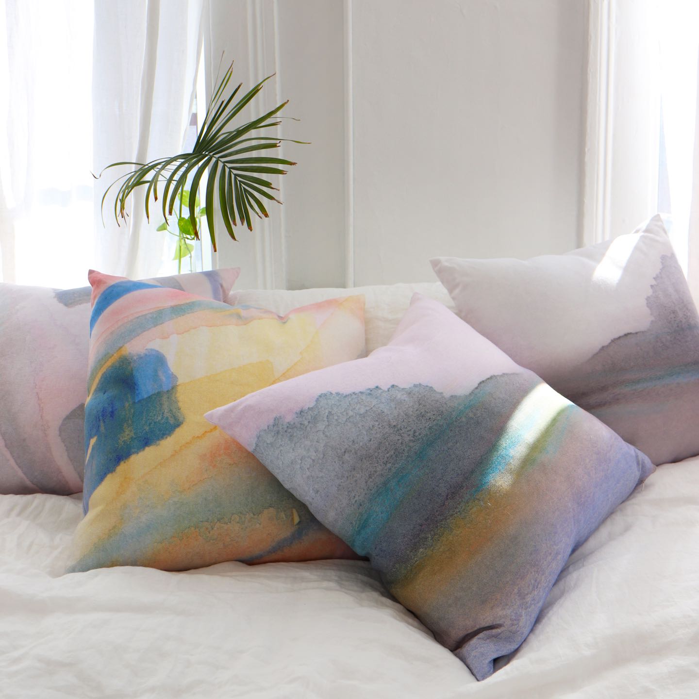 Three watercolor pillows on a bed in a room
