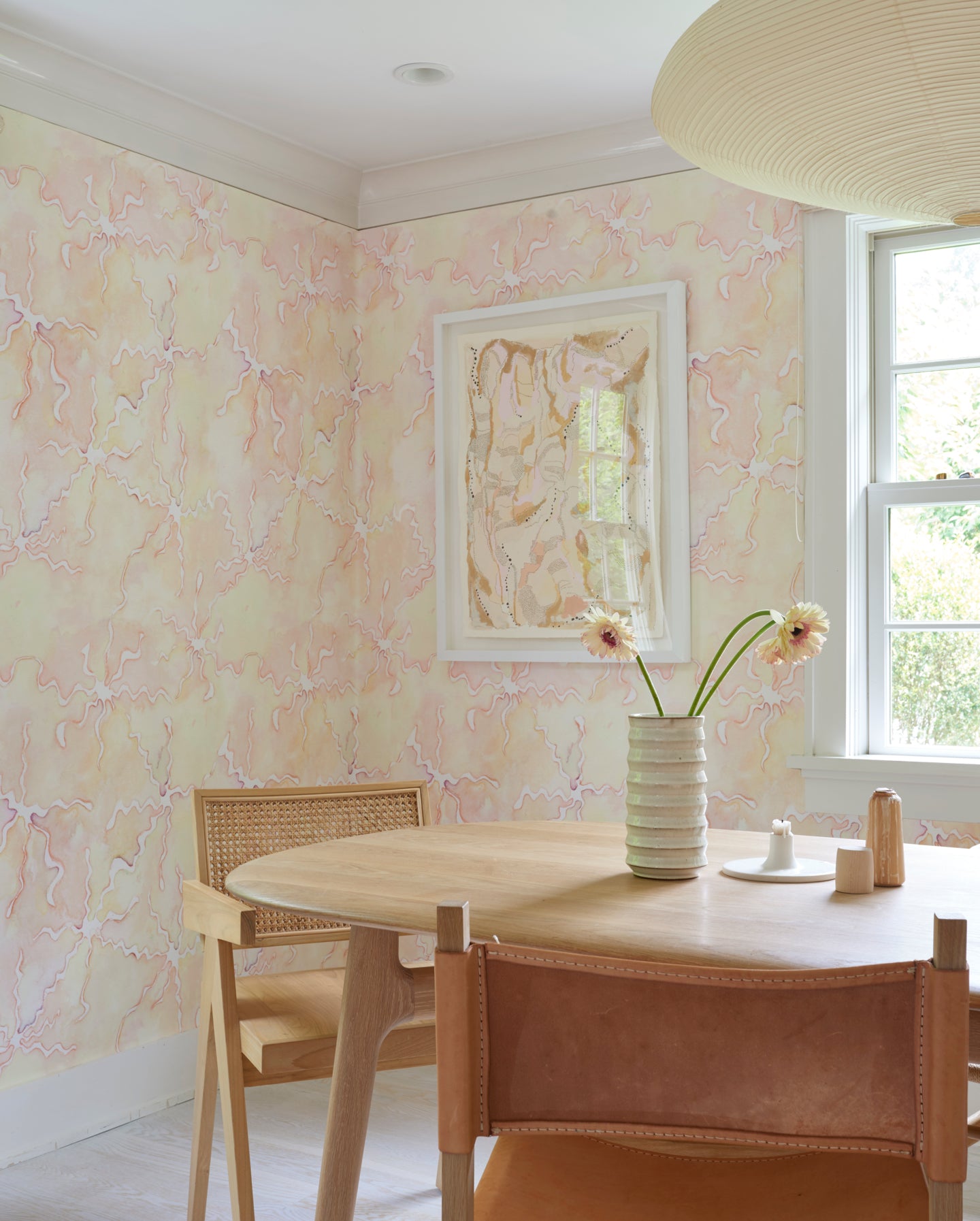 A dining room with pink wallpaper and a wooden table