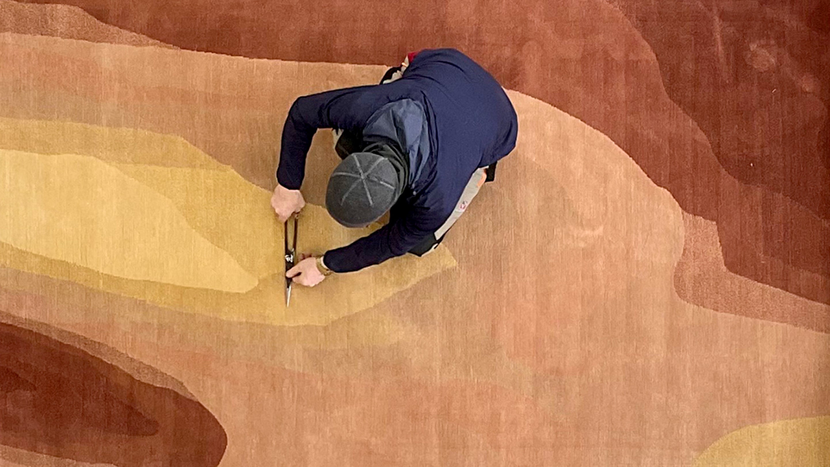 An aerial view of a man working on a rug