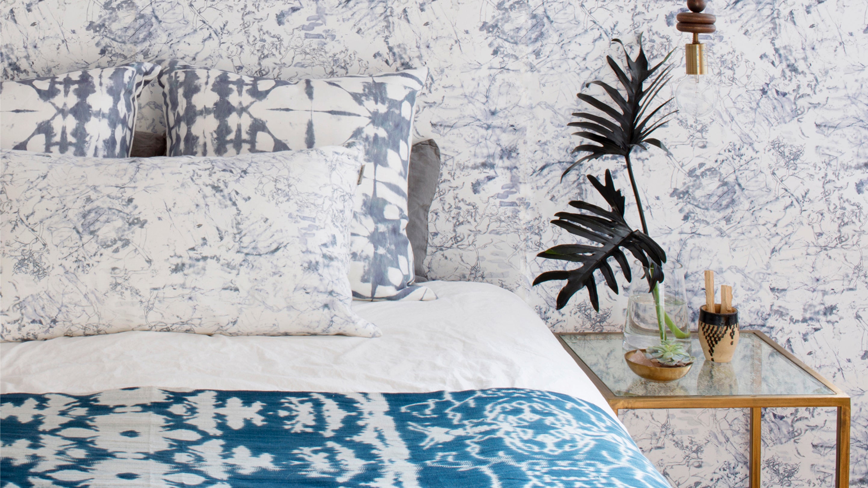 A bed with a blue and white pattern on the wall