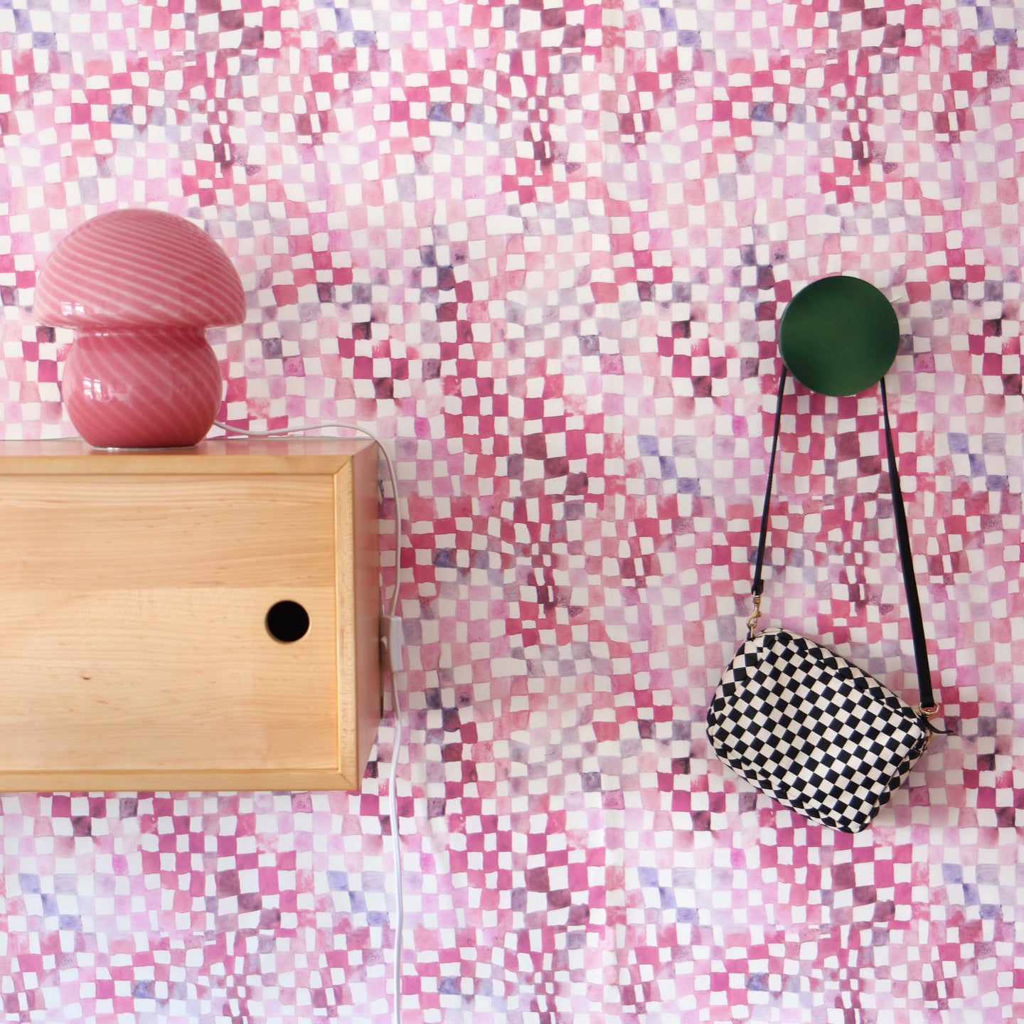 A pink and white checkered wallpaper with a wooden shelf and a bag