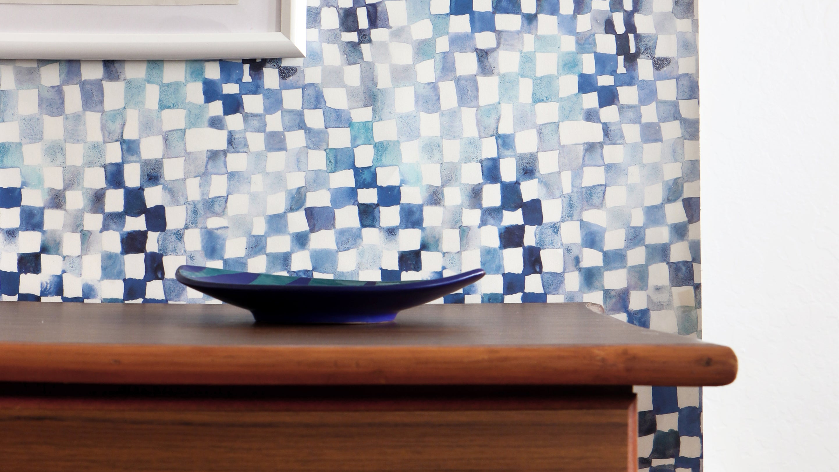 A blue and white tiled wall with a bowl in front of it
