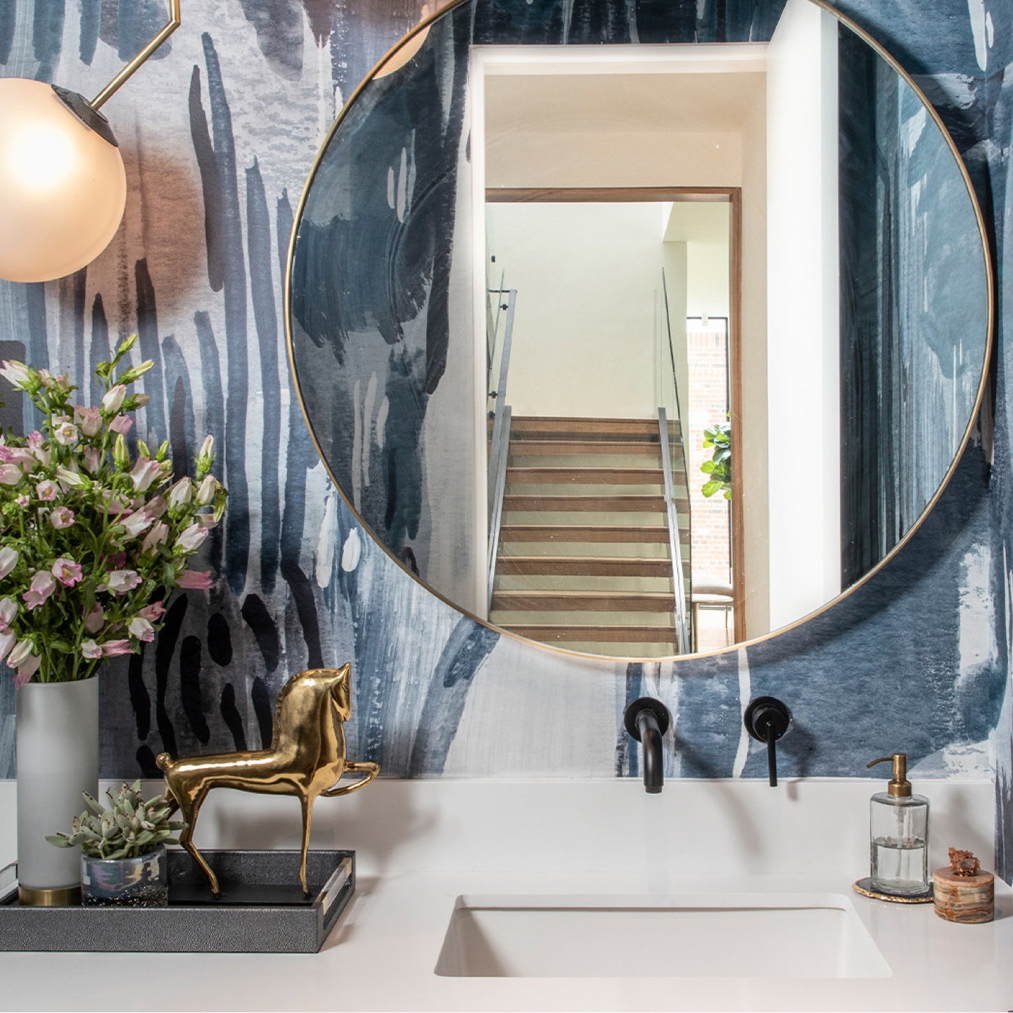 A bathroom with blue wallpaper and a mirror