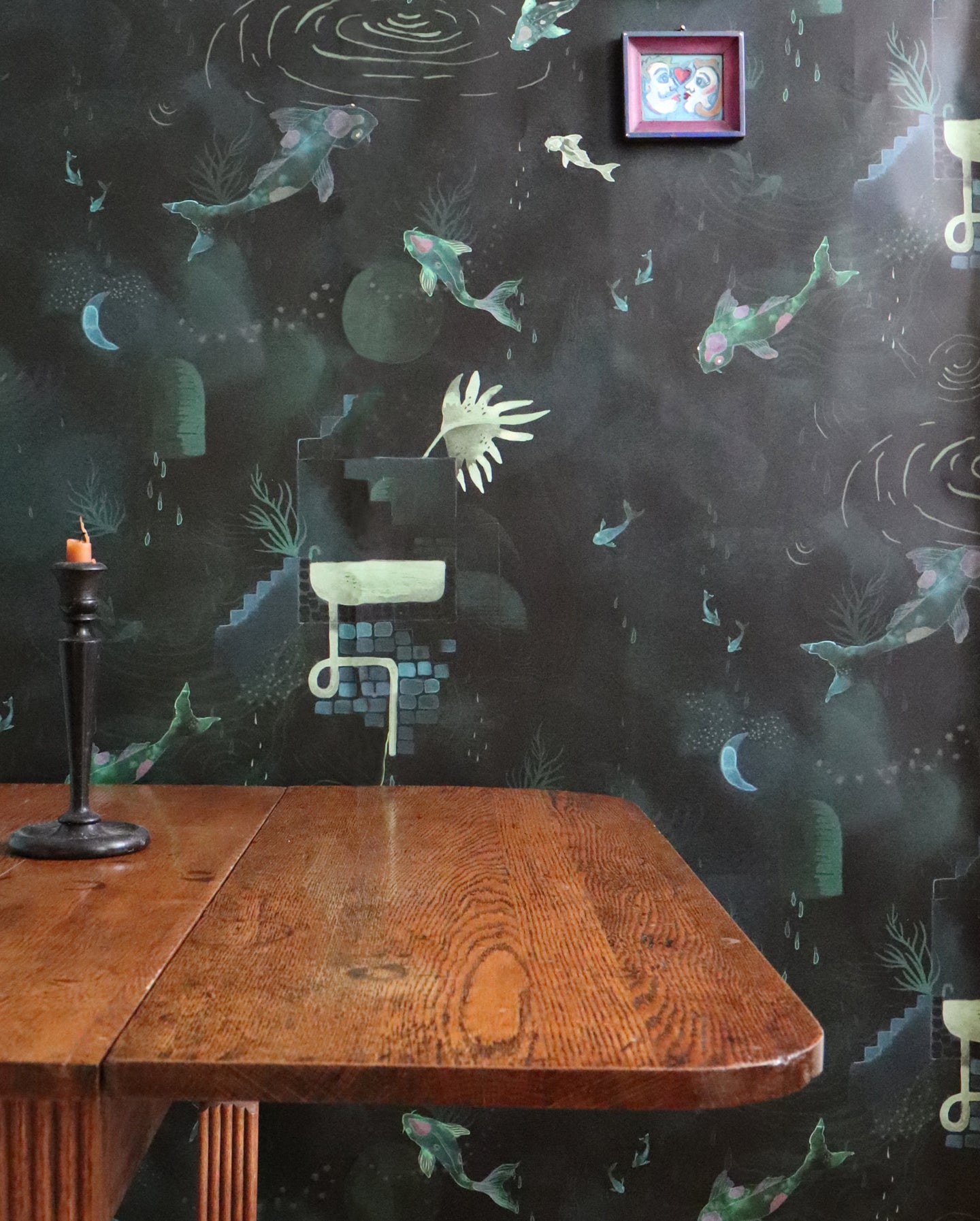 A room with a table and chairs, decorated in black wallpaper