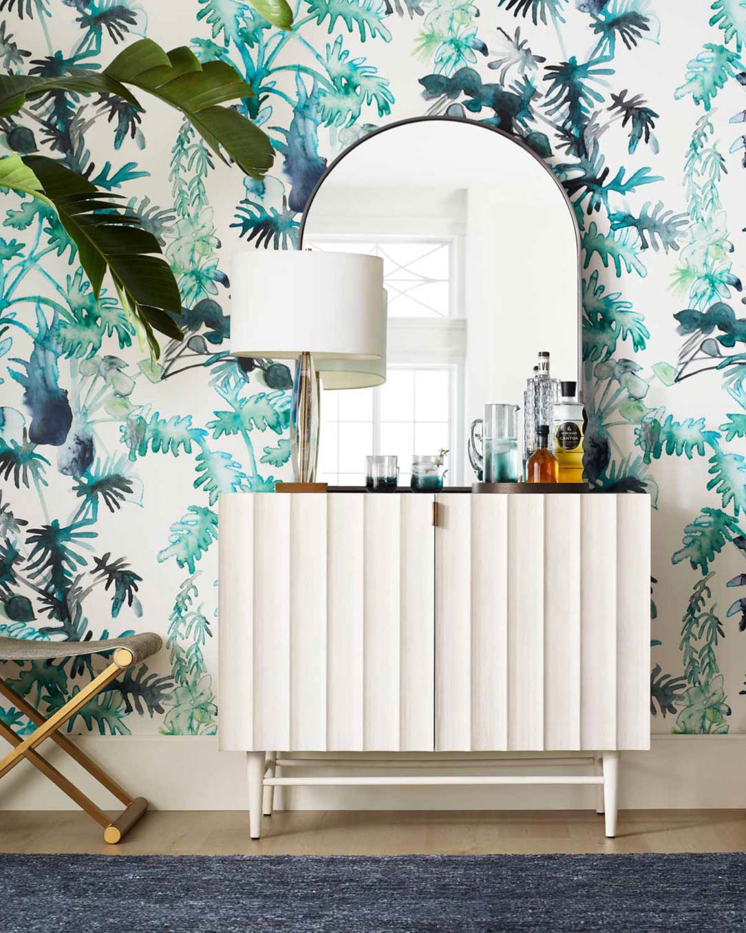 A living room with tropical wallpaper and mirror