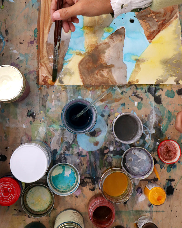 Artistic workspace with paint cans and a brush on a textured surface