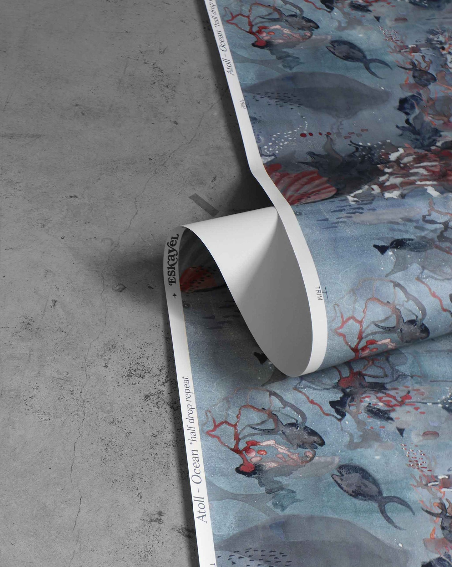 A roll of Atoll Wallpaper in the colorway Ocean, featuring fish and coral patterns with a blue base.