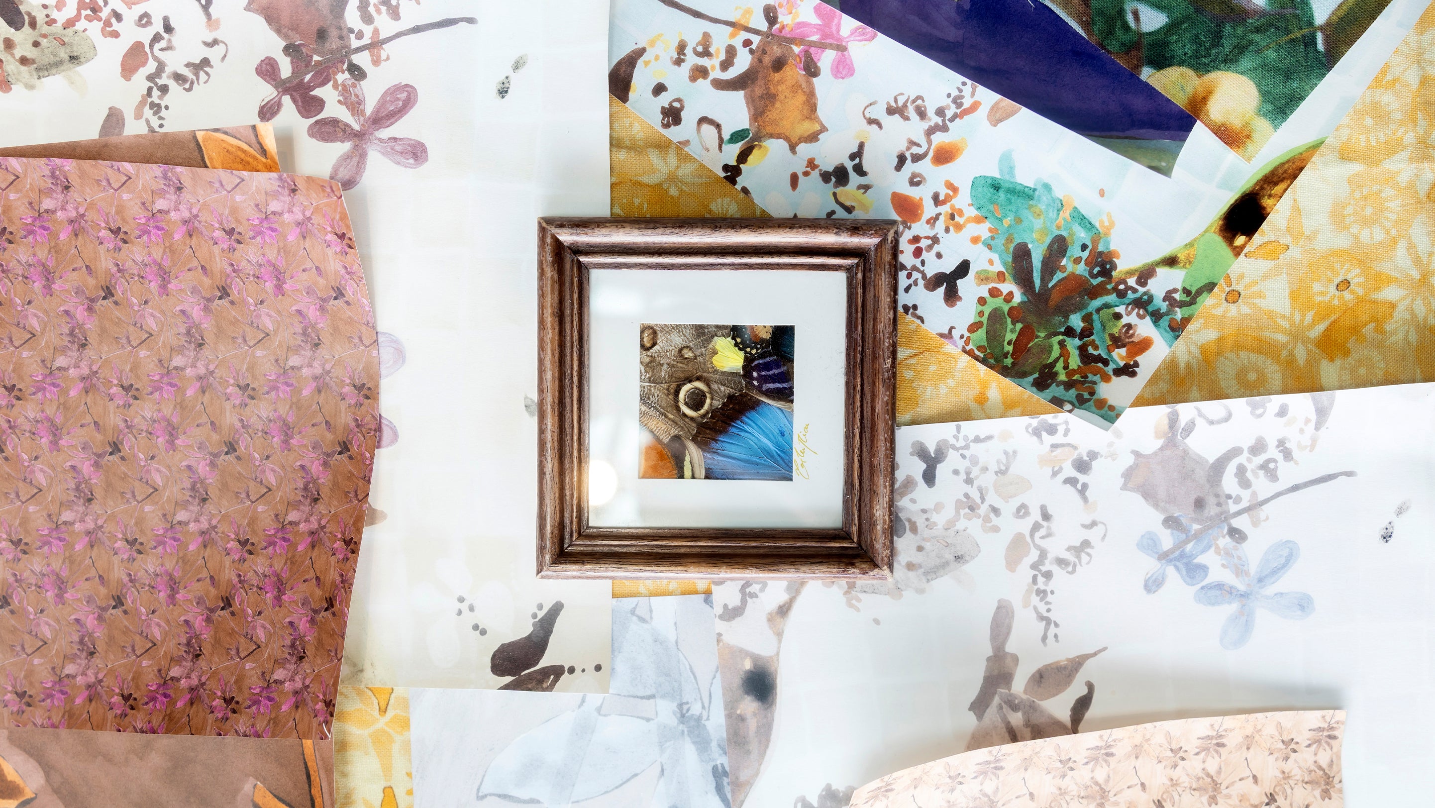 Collection of floral-patterned paper and a framed picture on a textured surface.