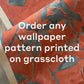 A close-up of Custom Grasscloth wallpaper in red with a blue floral pattern and white text stating, "Order any wallpaper pattern printed on grasscloth.
