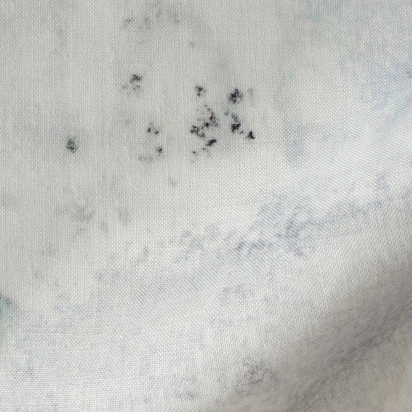 A close up of a white fabric with black spots on it