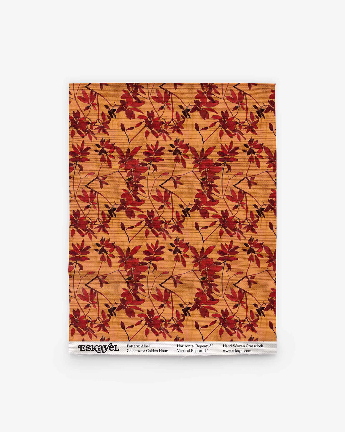 A rectangular sample of Alhelí Grasscloth in Golden Hour, featuring a golden yellow hand-woven texture with dark red, leafy floral sprigs.