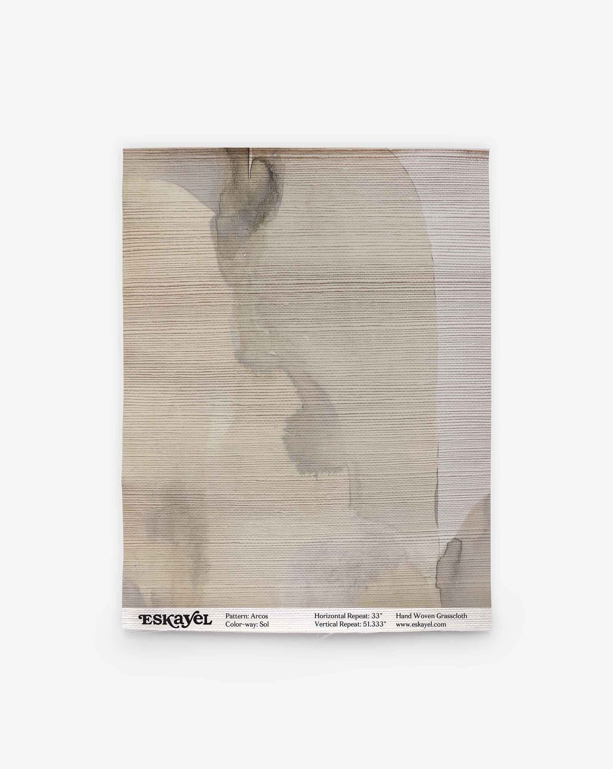 A square sample of Arcos Grasscloth in the Sol colorway, featuring gray and beige abstract watercolor-like patterns, is shown with product details at the bottom. Order a sample to experience the subtle elegance and sophisticated design of this wallpaper firsthand.