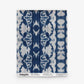 A square swatch of Bali Stripe Grasscloth in the Indigo Ikat design, featuring a bold, symmetrical blue and white pattern with labeled details along the bottom edge.